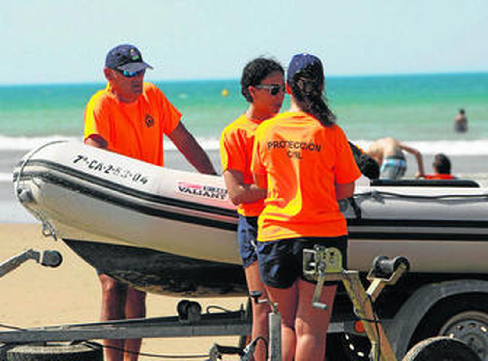 Miembros de Protección Civil en la playa de la Barrosa junto a una lancha de salvamento.