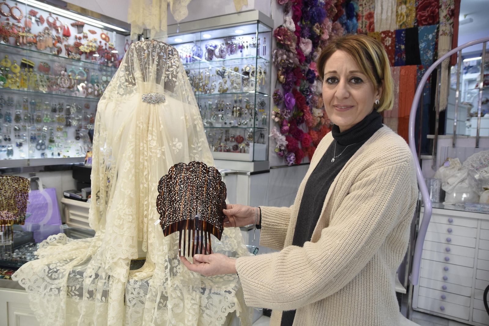 Una de las dependientas de la tienda Abril muestra una peina y una mantilla detrás.