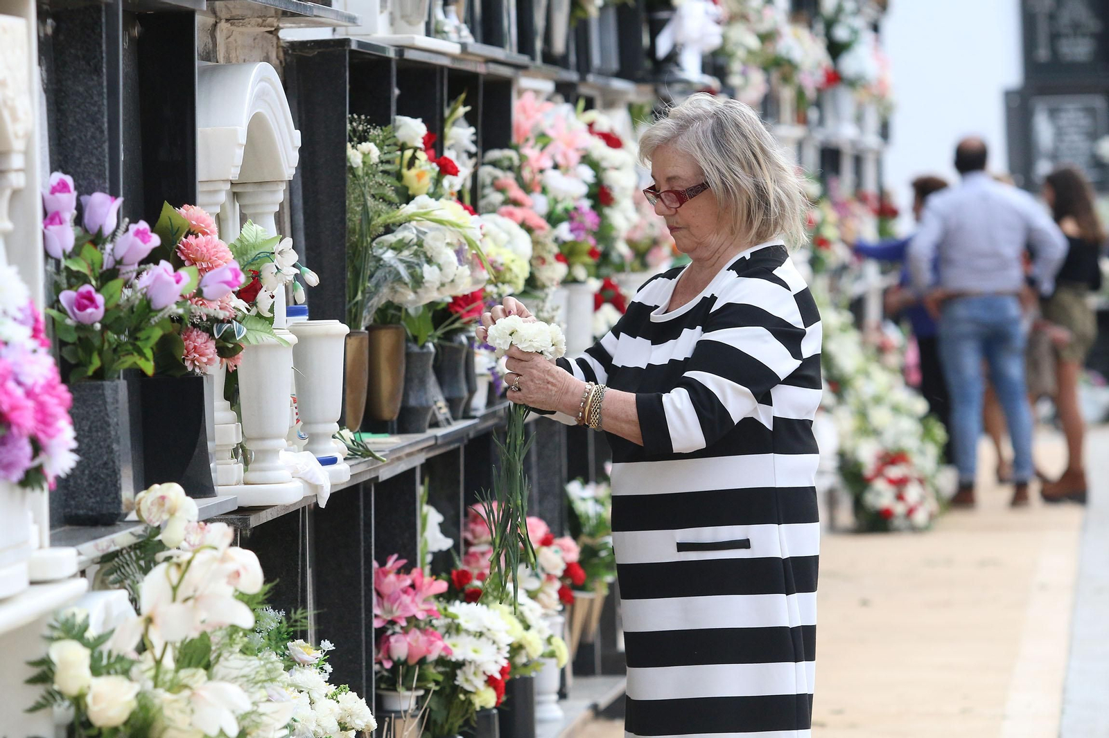 Una mujer arregla el ramo de claves en el cementerio de San José.
