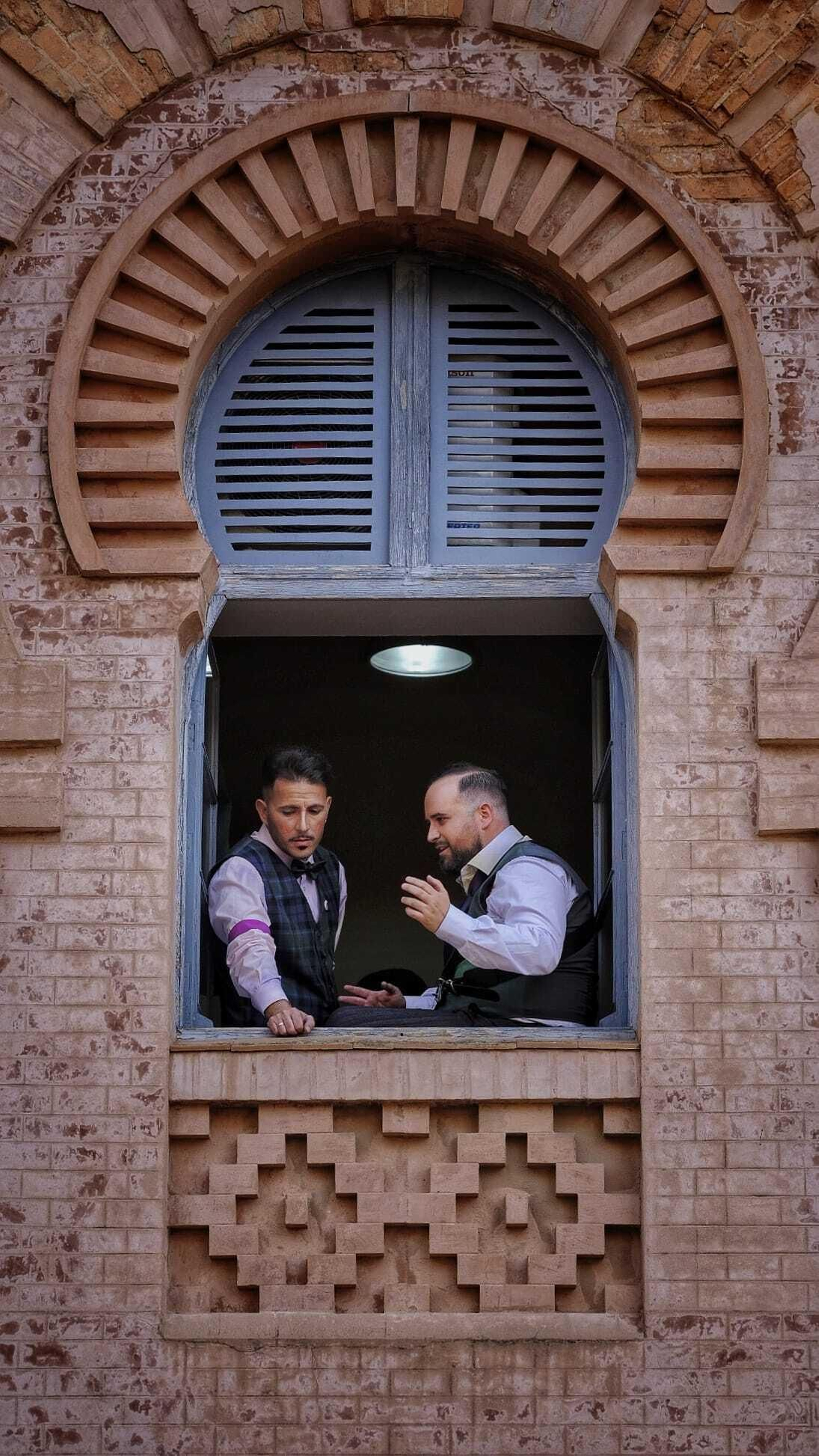 Componentes de la comparsa 'El club de los ignorantes' , aplena luz del día, , asomados a una de las ventanas del teatro