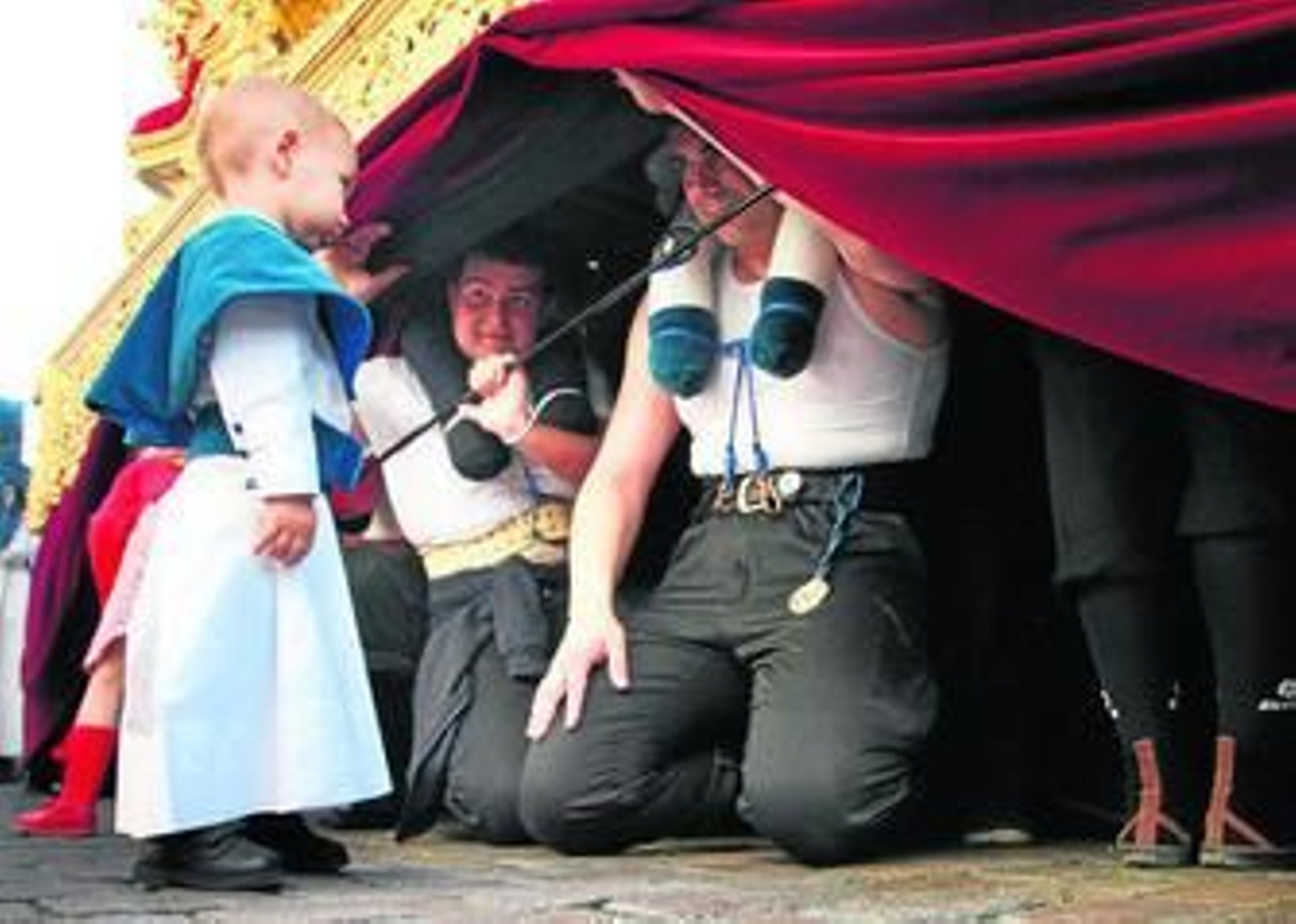 Un pequeño monaguillo va a 'visitar' a su padre bajo las trabajaderas del misterio de la Flagelación.