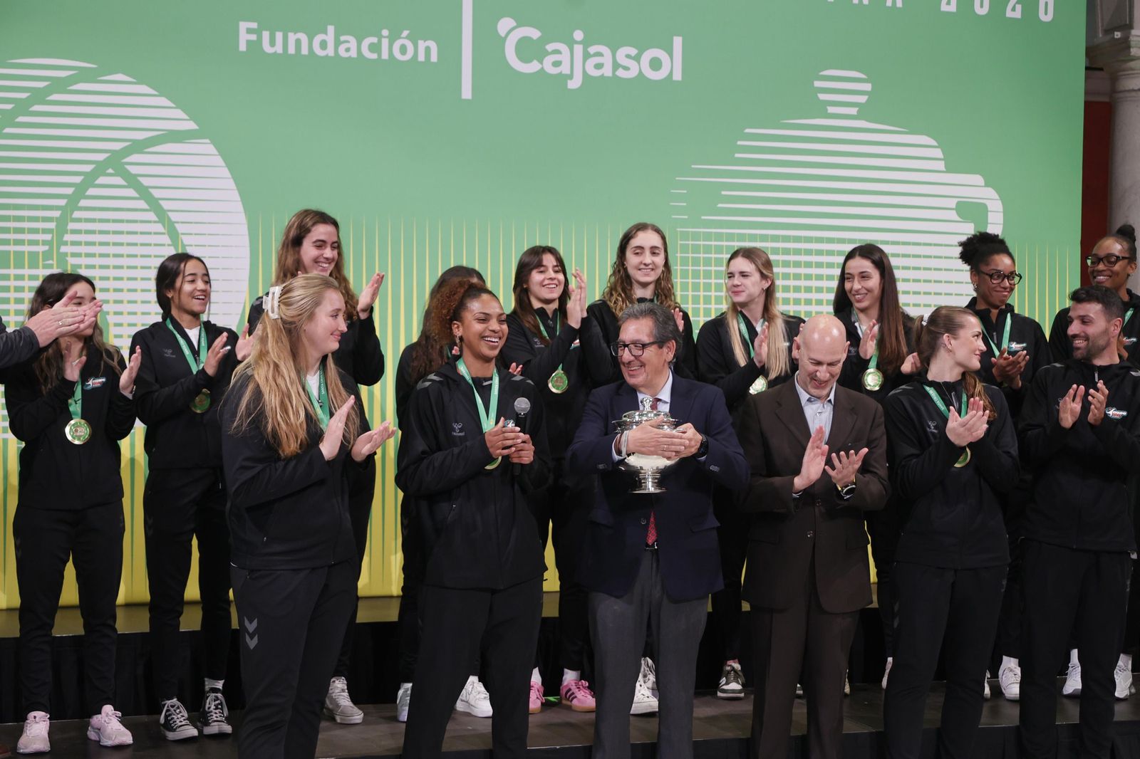 Antonio Pulido agarra la Copa entre el aplauso de todas las jugadoras, dirigentes y entrenador del equipo.
