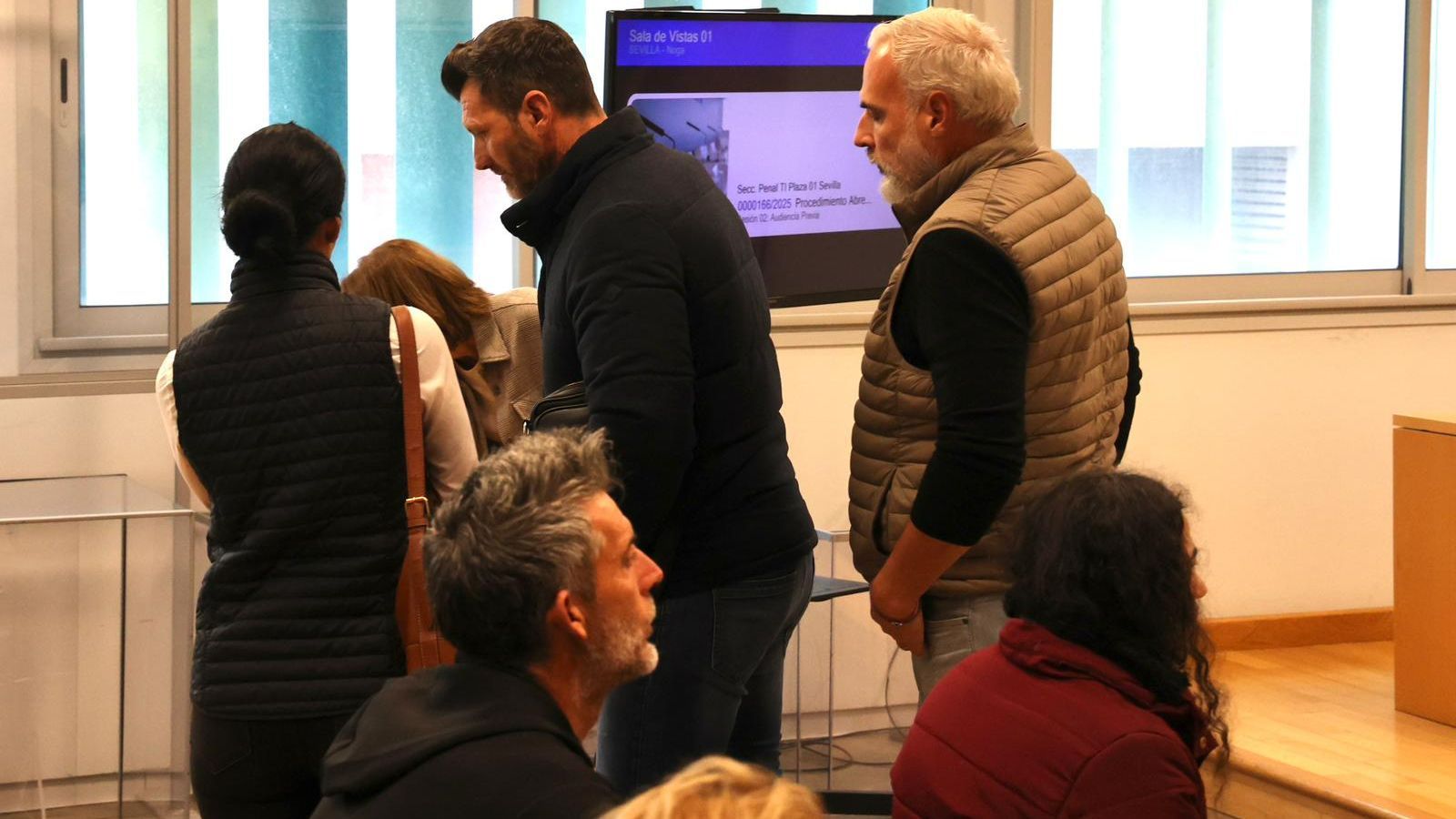 El padre de la víctima (de pie al fondo) pasa cerca de la acusada (a la derecha, de rojo), este lunes en el juzgado.