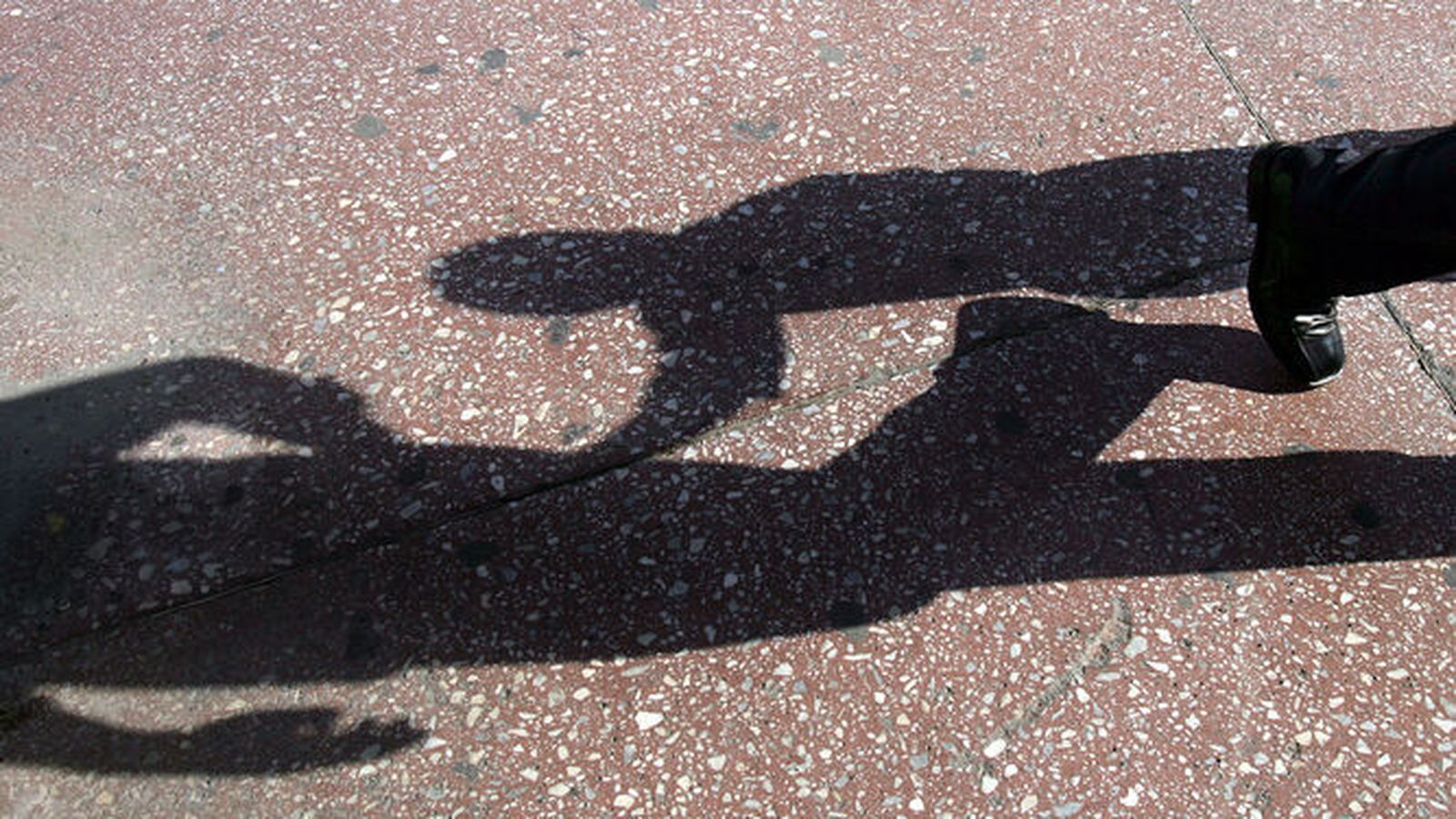 Sombra de un niño proyectada en la calzada.