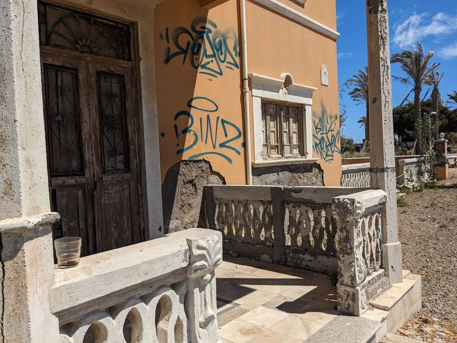 Un vaso con café reposa en la entrada a la vivienda desde la playa.