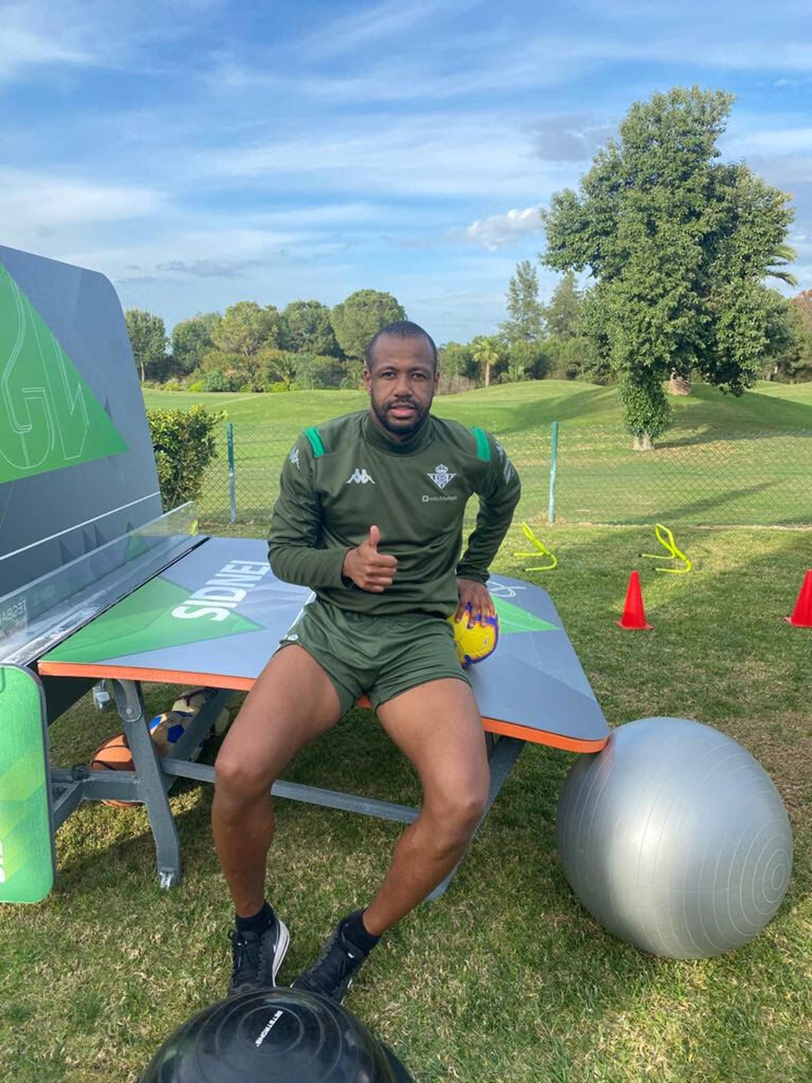 Sidnei posa sentado sobre su mesa de fútbol-tenis en un entrenamiento en el jardín de su casa.