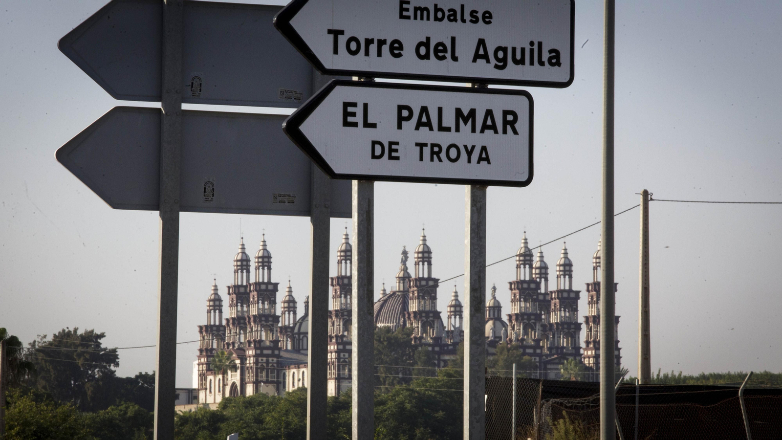 Señales de tráfico del nuevo municipio y del embalse. Al fondo, la basílica del Palmar.