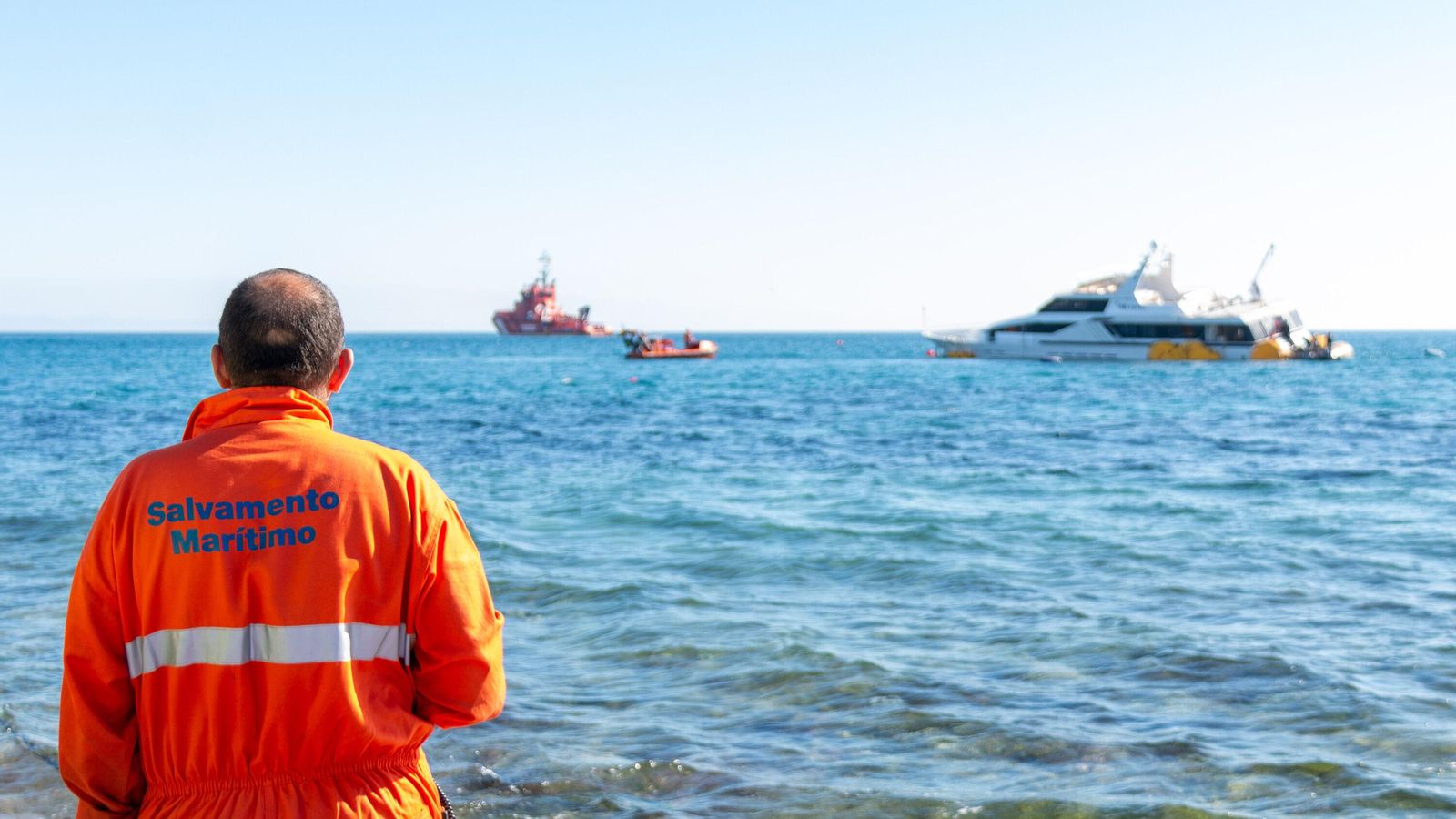Un trabajador de Salvamento Marítimo ve desde la orilla como se llevan el yate encallado en Carchuna tras 10 días de trabajo