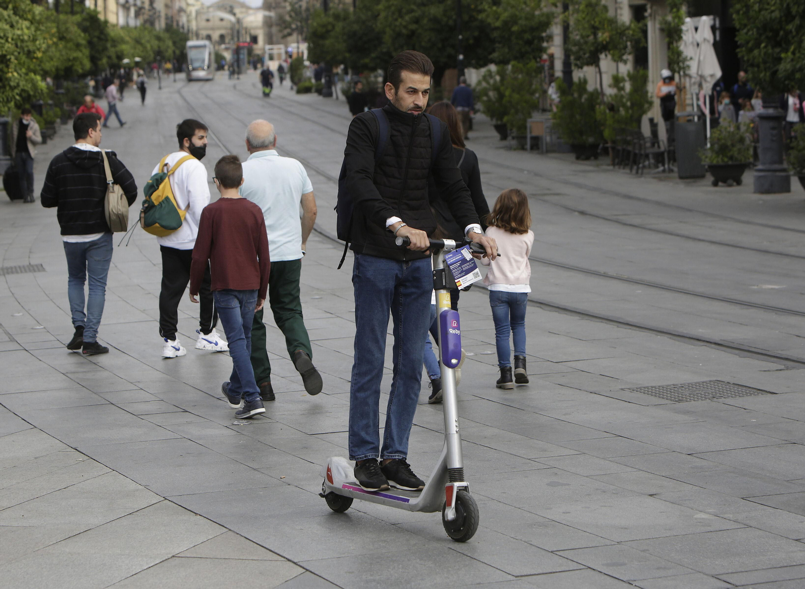 Un hombre circula en patinete por la Avenida de la Constitución.