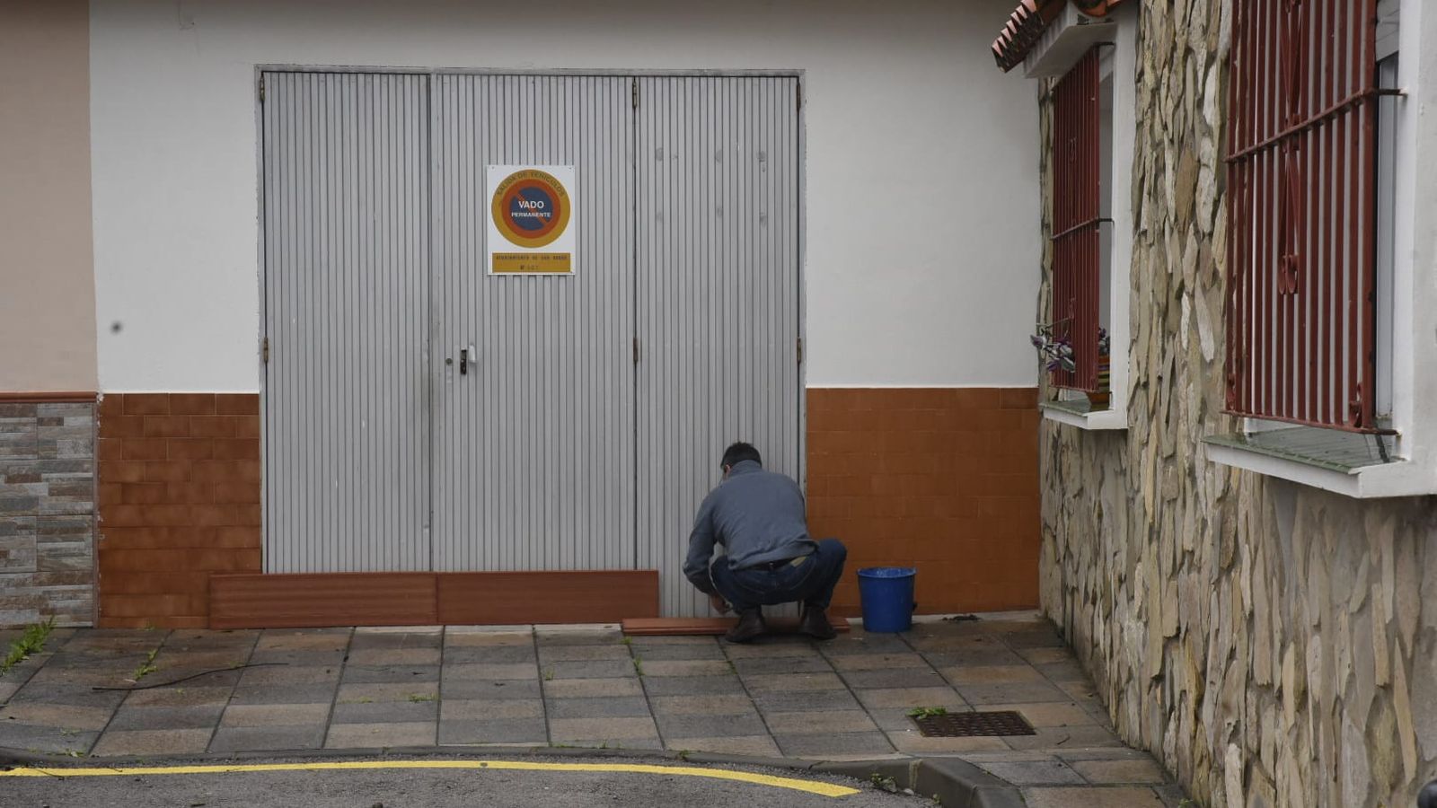 Un hombre pone rasillones en la puerta de su garaje.
