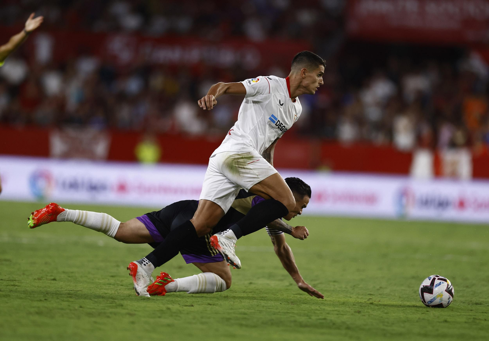 Erik Lamela avanza con la pelota ante un jugador del Valladolid caído.