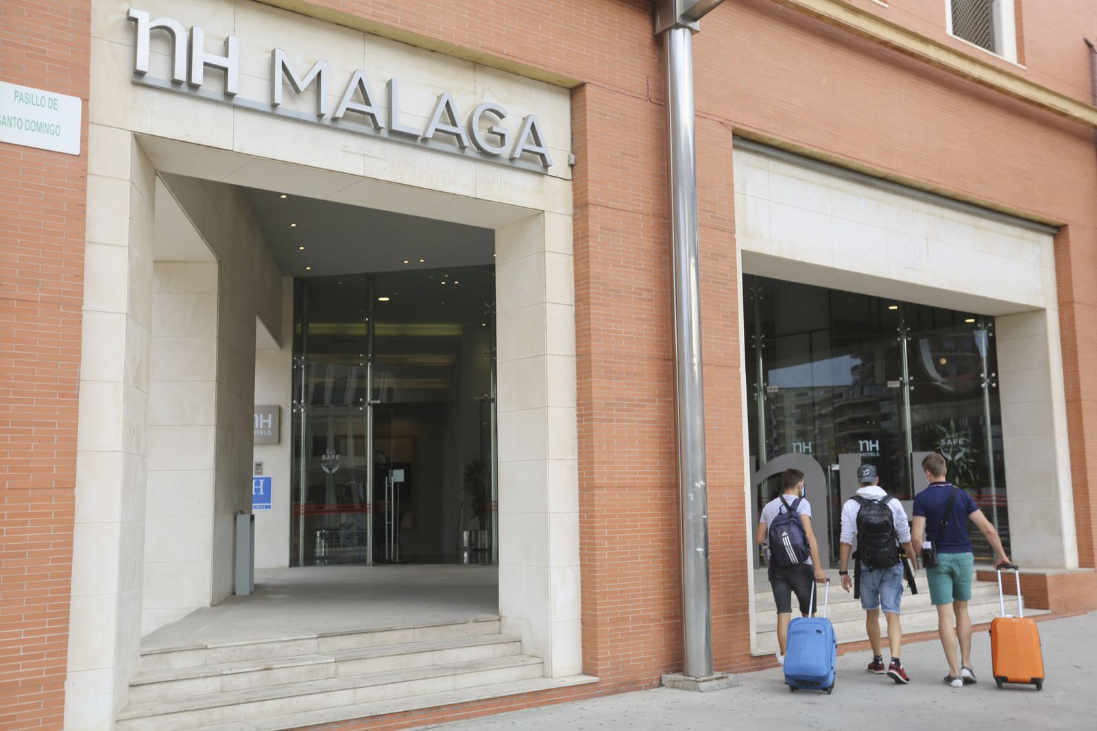 Tres turistas en la puerta del hotel NH en Málaga capital.