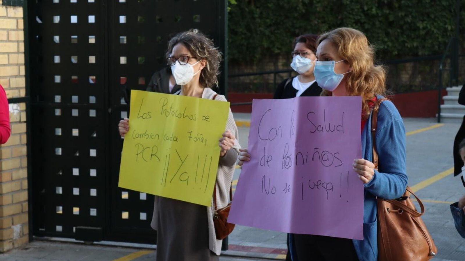 Varias madres sostienen carteles pidiendo PCR para todos los niños.