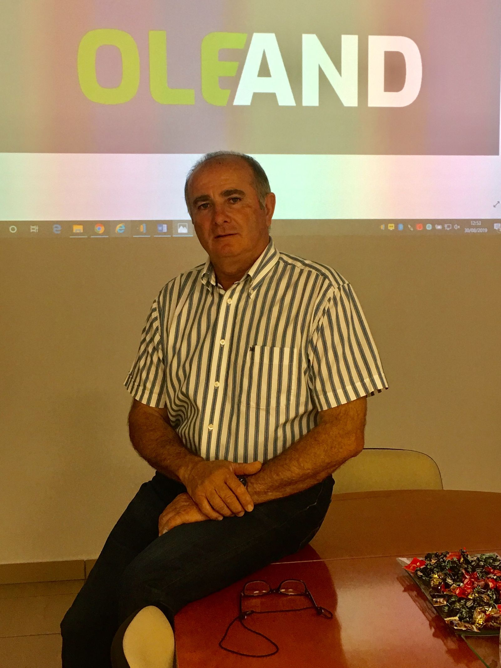 Antonio Candil ante el logo de la nueva cooperativas Oleand.