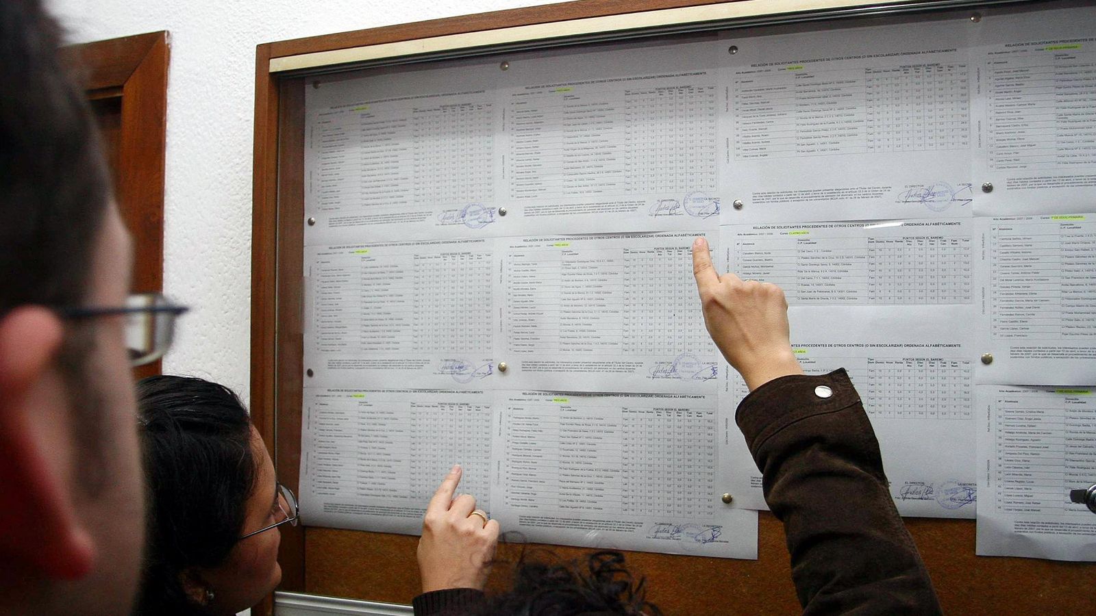 Las familias comprueban las listas de alumnos admitidos en un colegio concertado.