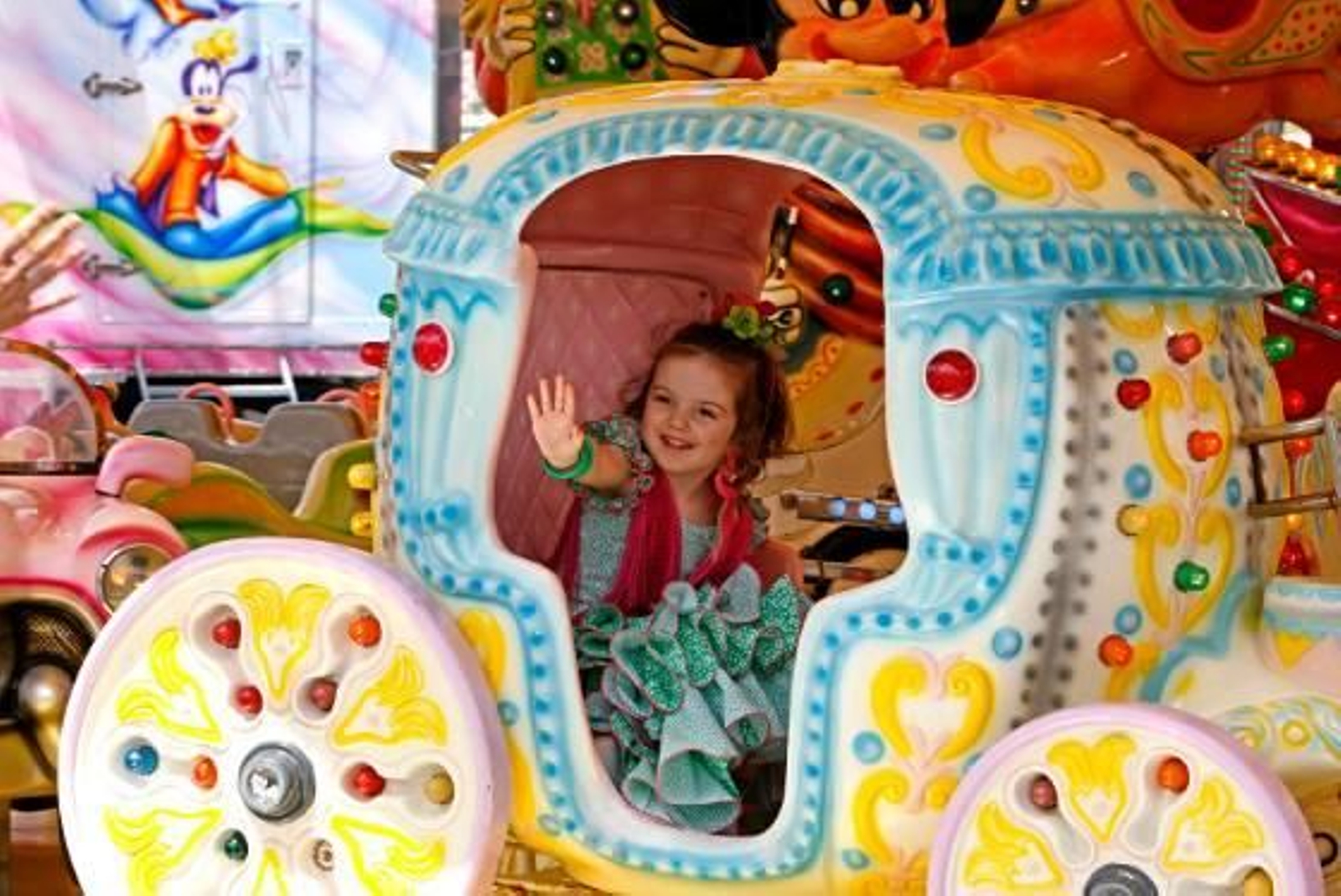 Una pequeña ayer vestida de flamenca saluda a sus padres mientras disfruta en las atracciones.

Foto: Pascual