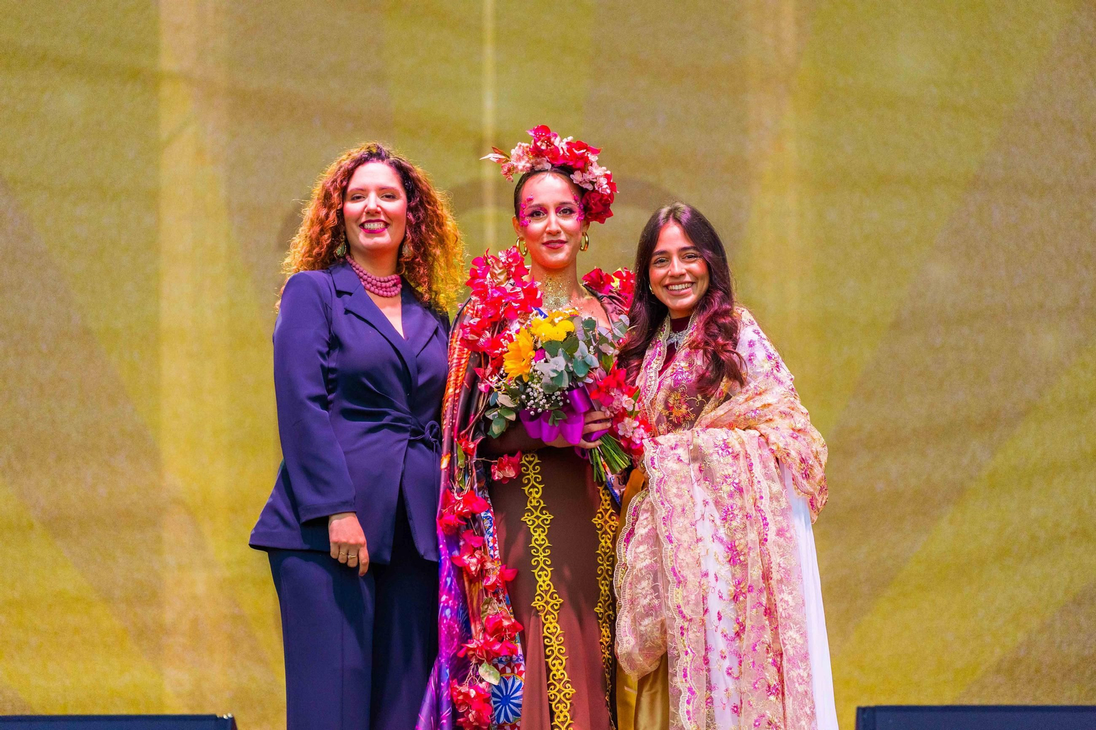 Beatriz Pascual Martín, representa con su disfraz a la Feria del Carmen y de la Sal de La Isla. Su traje evoca el folclore y las flores tradicionalmente presentes en los trajes de flamenca y otros elementos de esta fiesta
