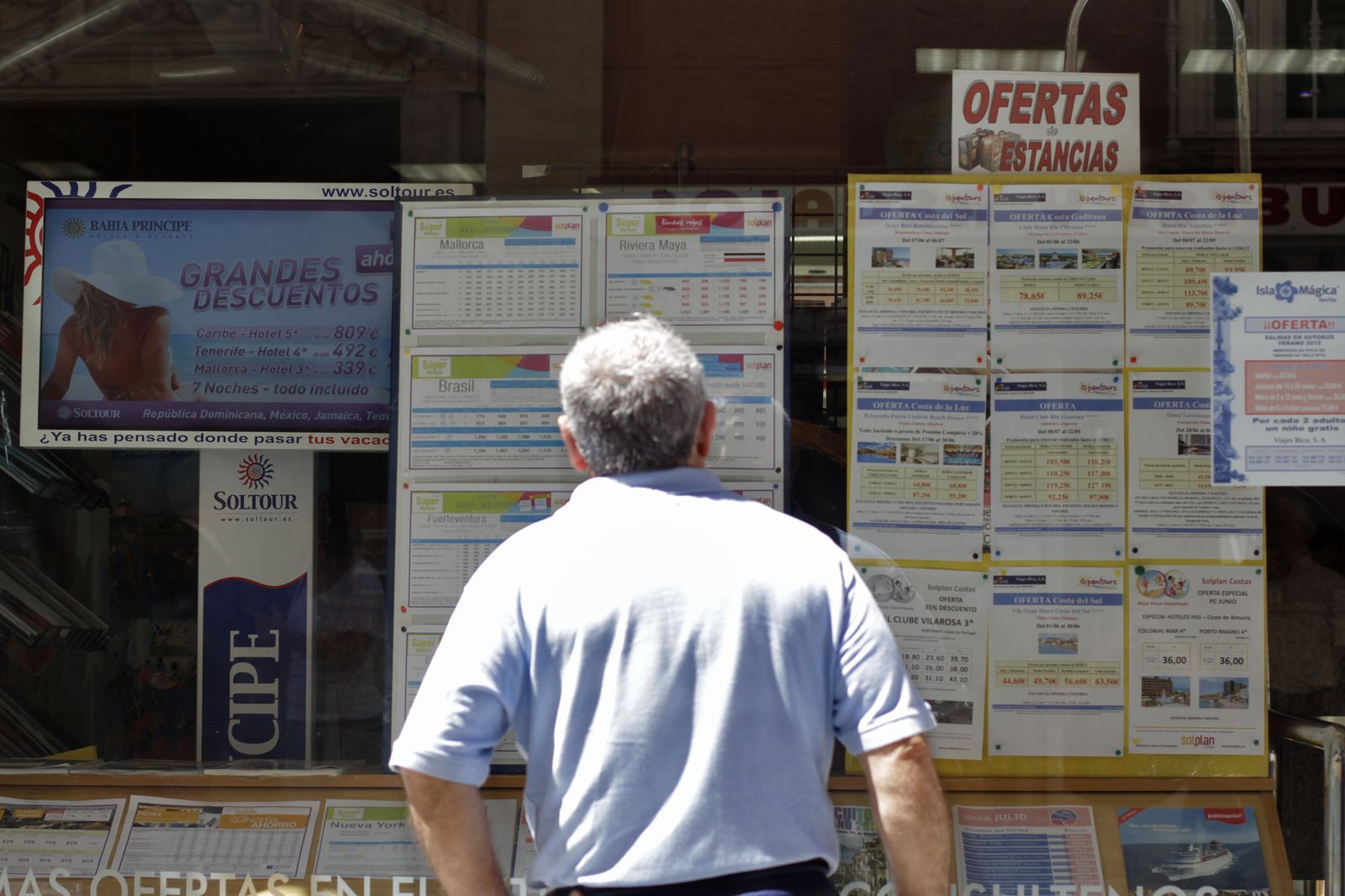 Un hombre observa el escaparate de una agencia de viajes.