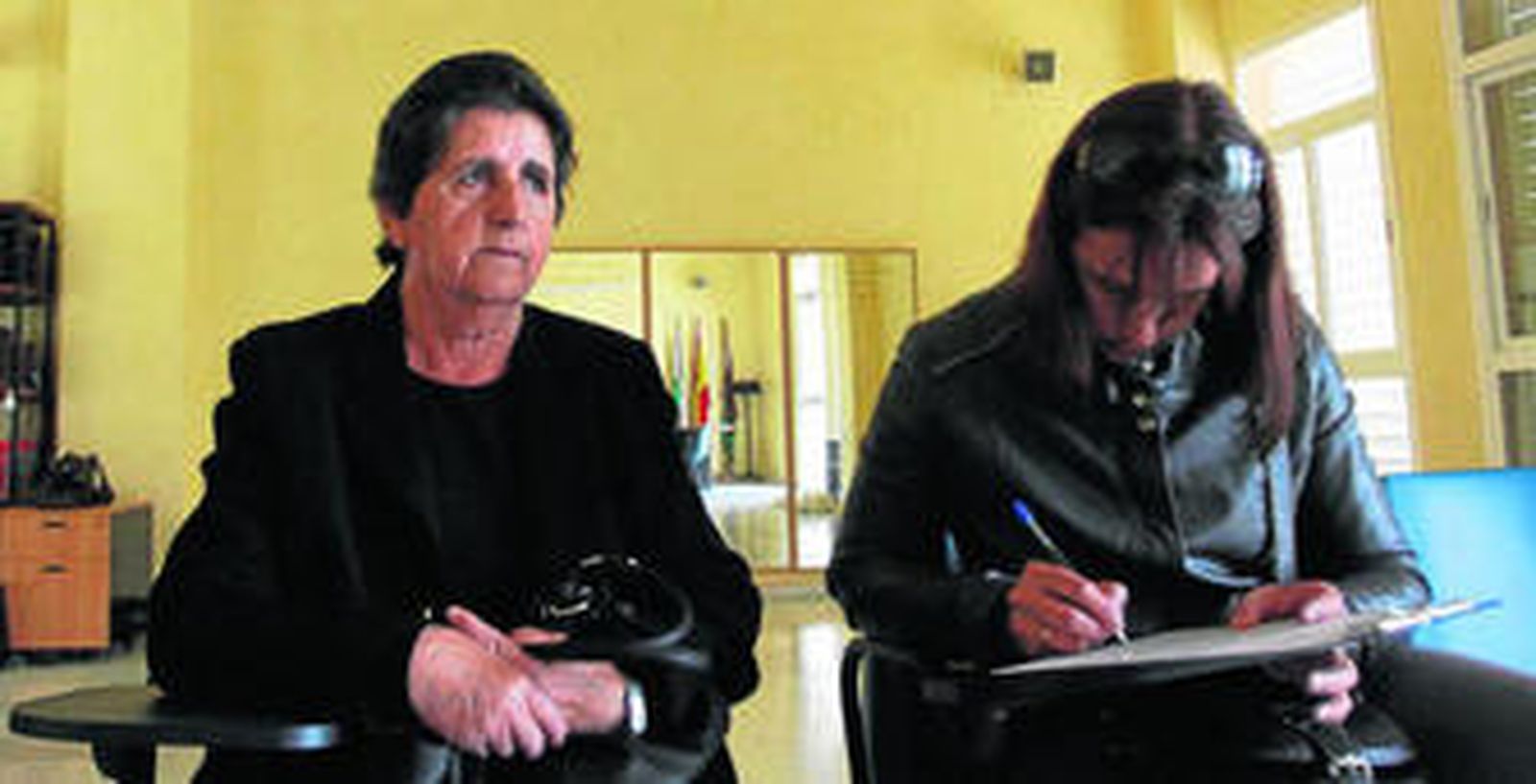 Una joven escribe un texto en compañía de una familiar afectada por los bebés 'robados'.