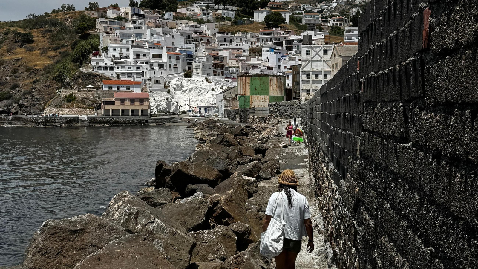 Una persona pasea por la escollera de La Caleta
