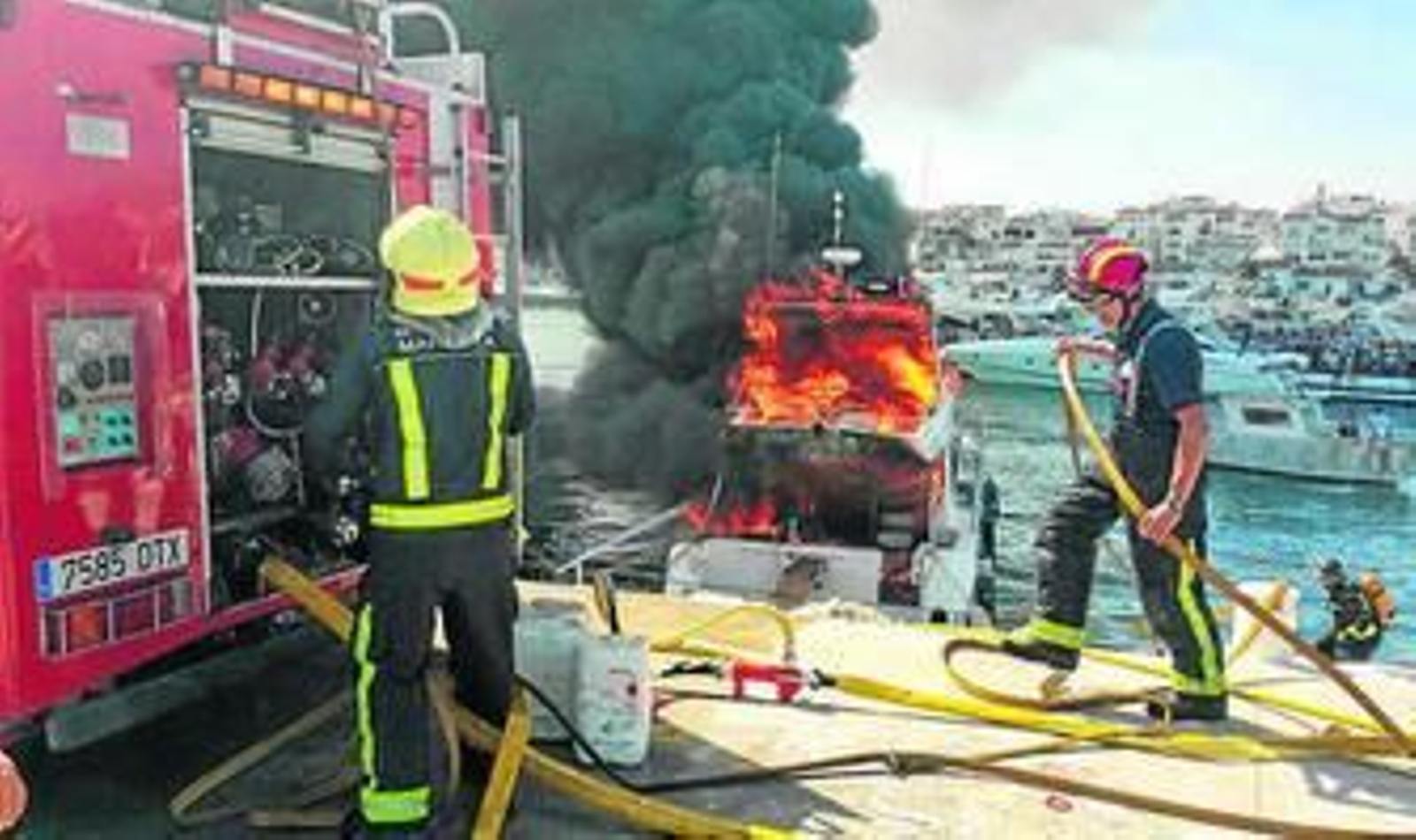 Bomberos sofocando las llamas del barco incendiado.