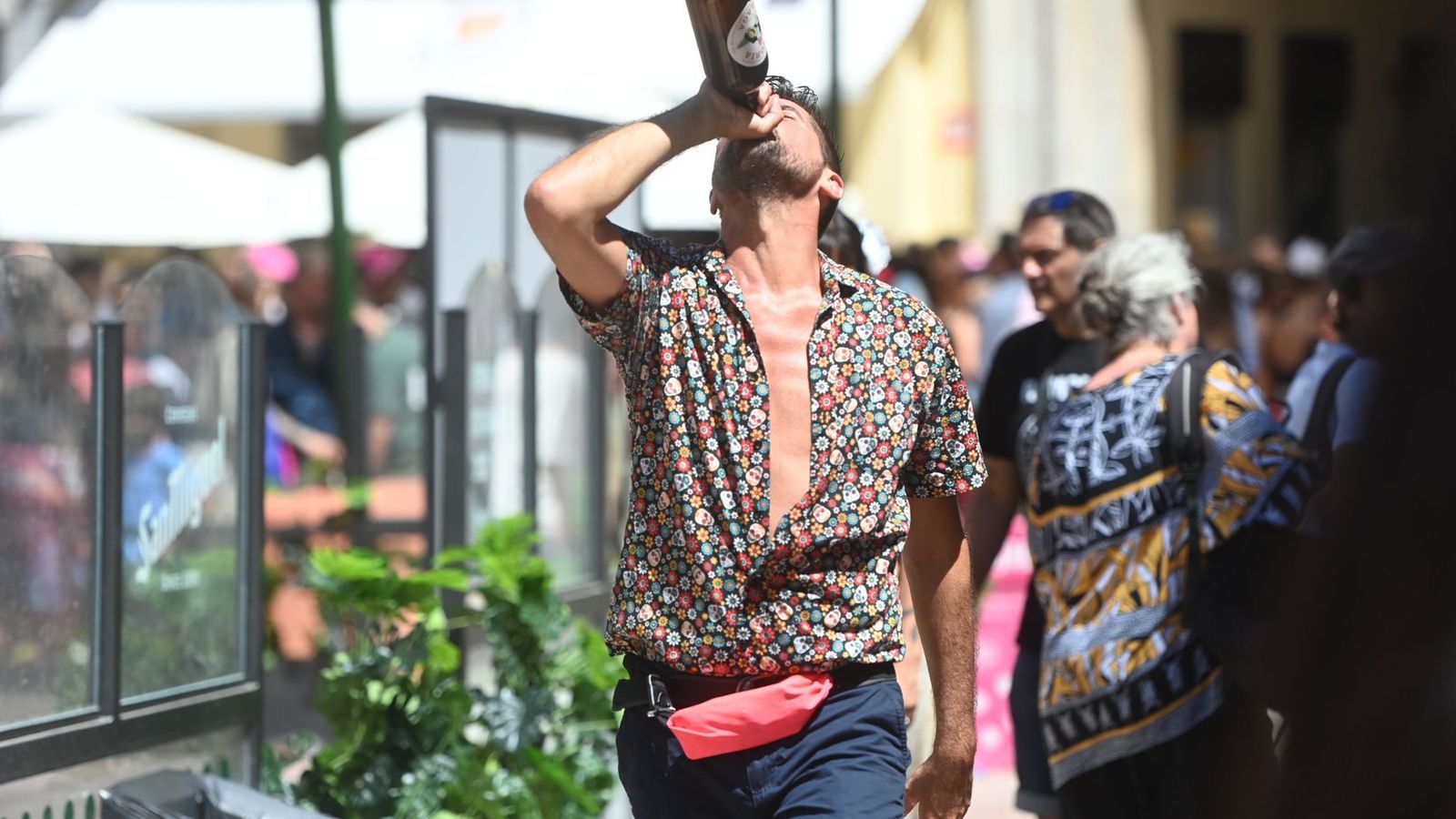 Un chico bebe una botella de cerveza en la Feria del centro.