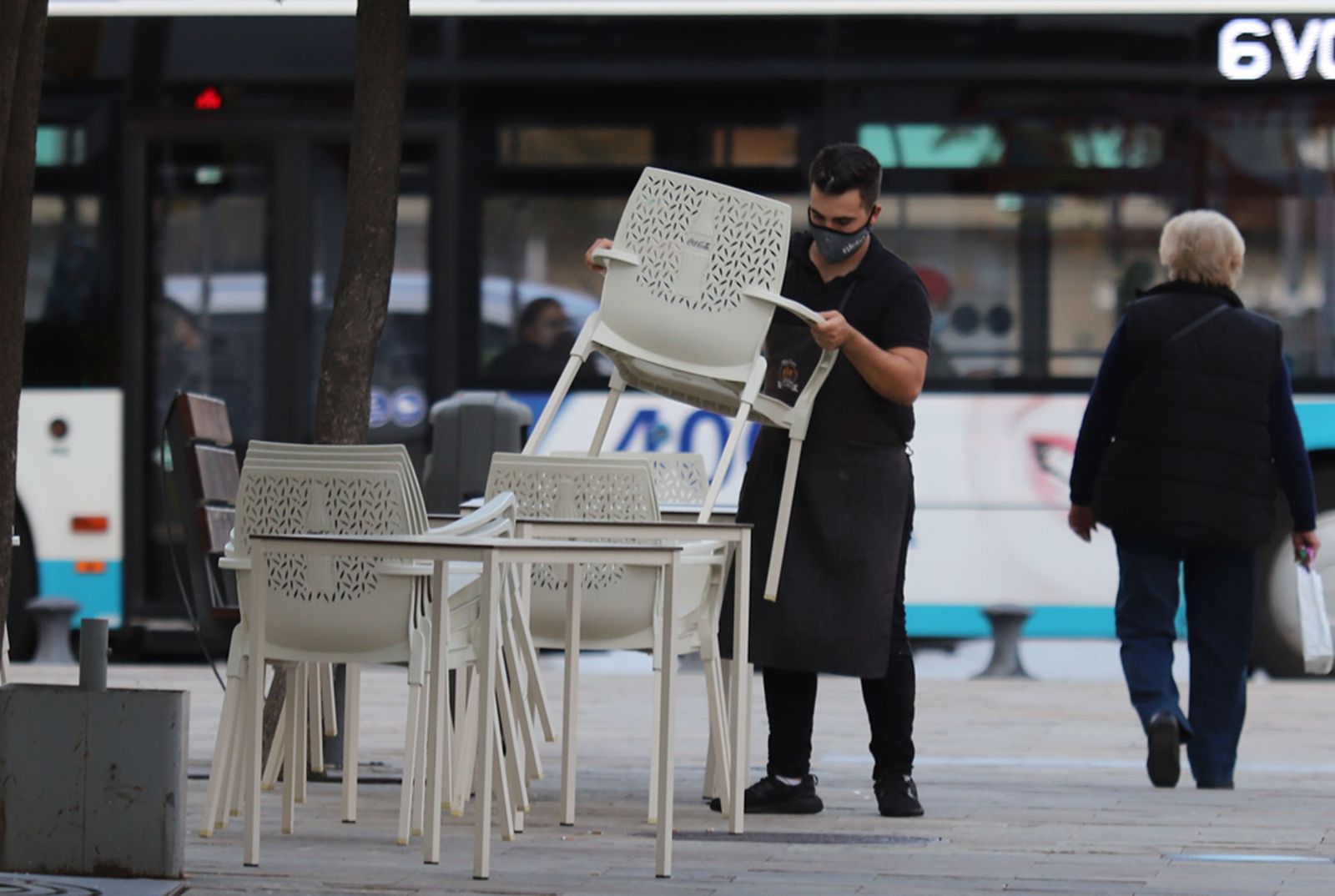 Un camarero recoge las sillas y mesas de una terraza en Huelva.