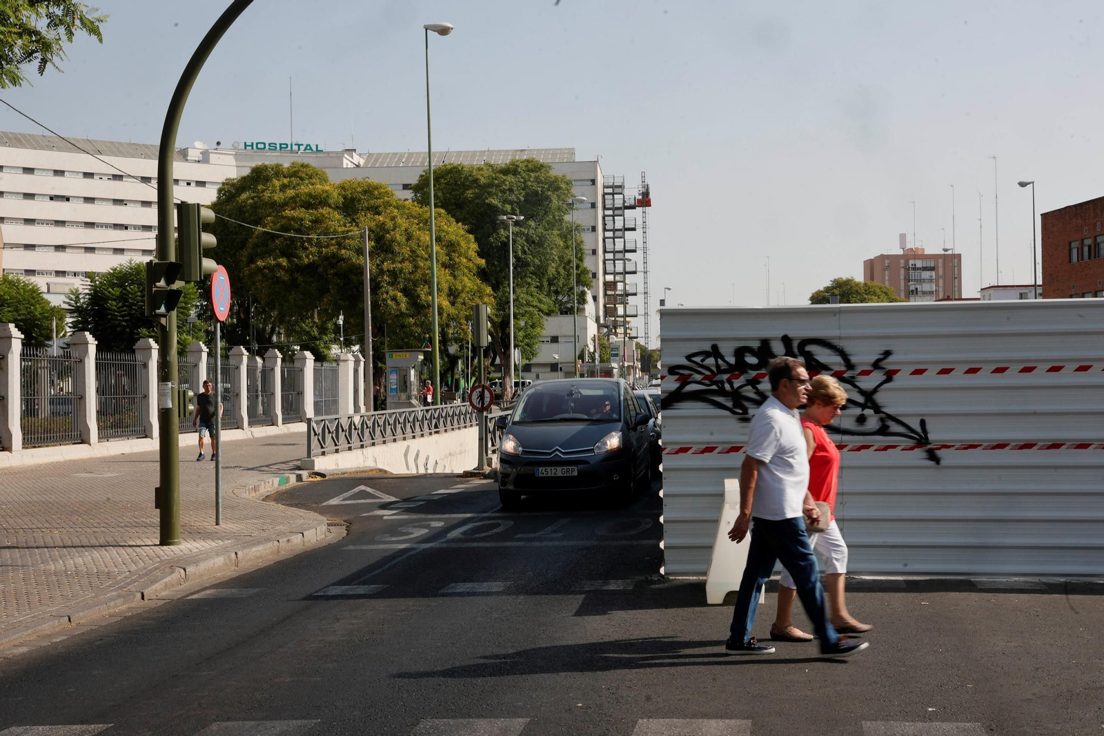 Una fila de vechículos circulan por el único carril disponible en la entrada principal del Hospital Virgen Macarena.