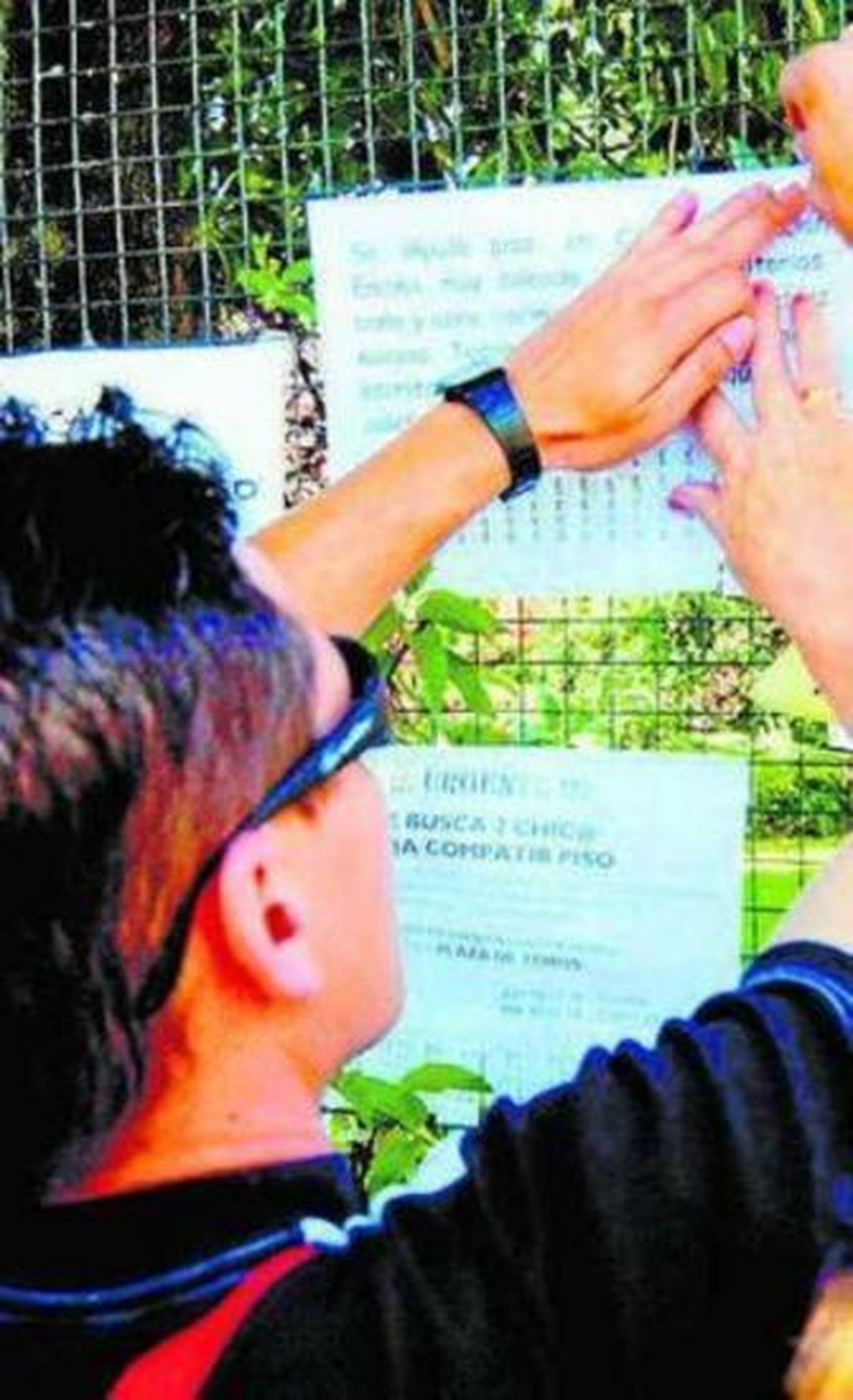 Un señor coloca un cartel para alquilar su vivienda.