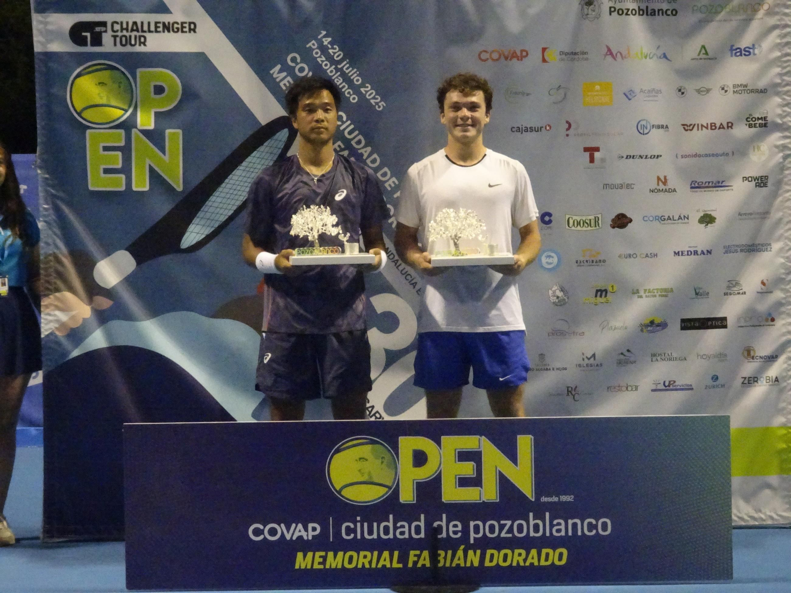 Iñaki Montes y Fajing Sun sostienen el premio de campeones.