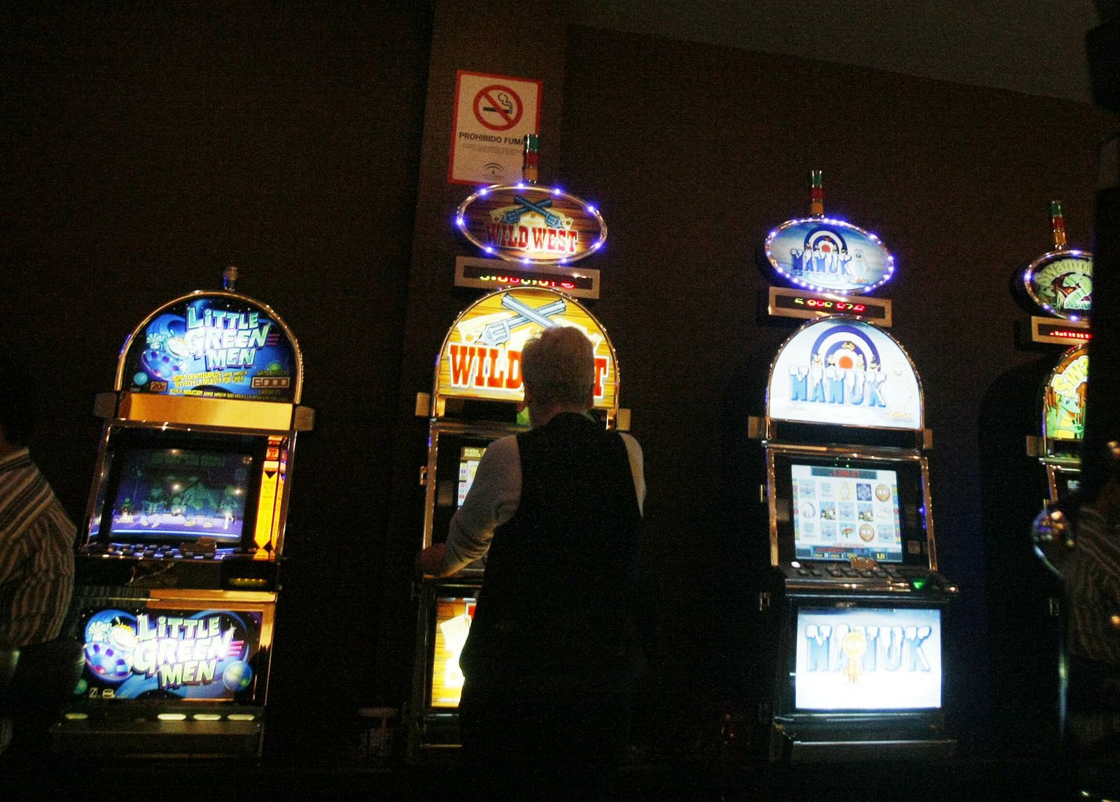 Un hombre juega a una de las máquinas tragaperras de un salón de juegos.