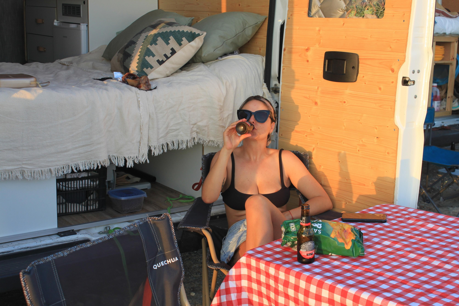 Thalia disfruta de una cerveza junto a su furgoneta camperizada. Thalia disfruta de una cerveza junto a su furgoneta camperizada.
