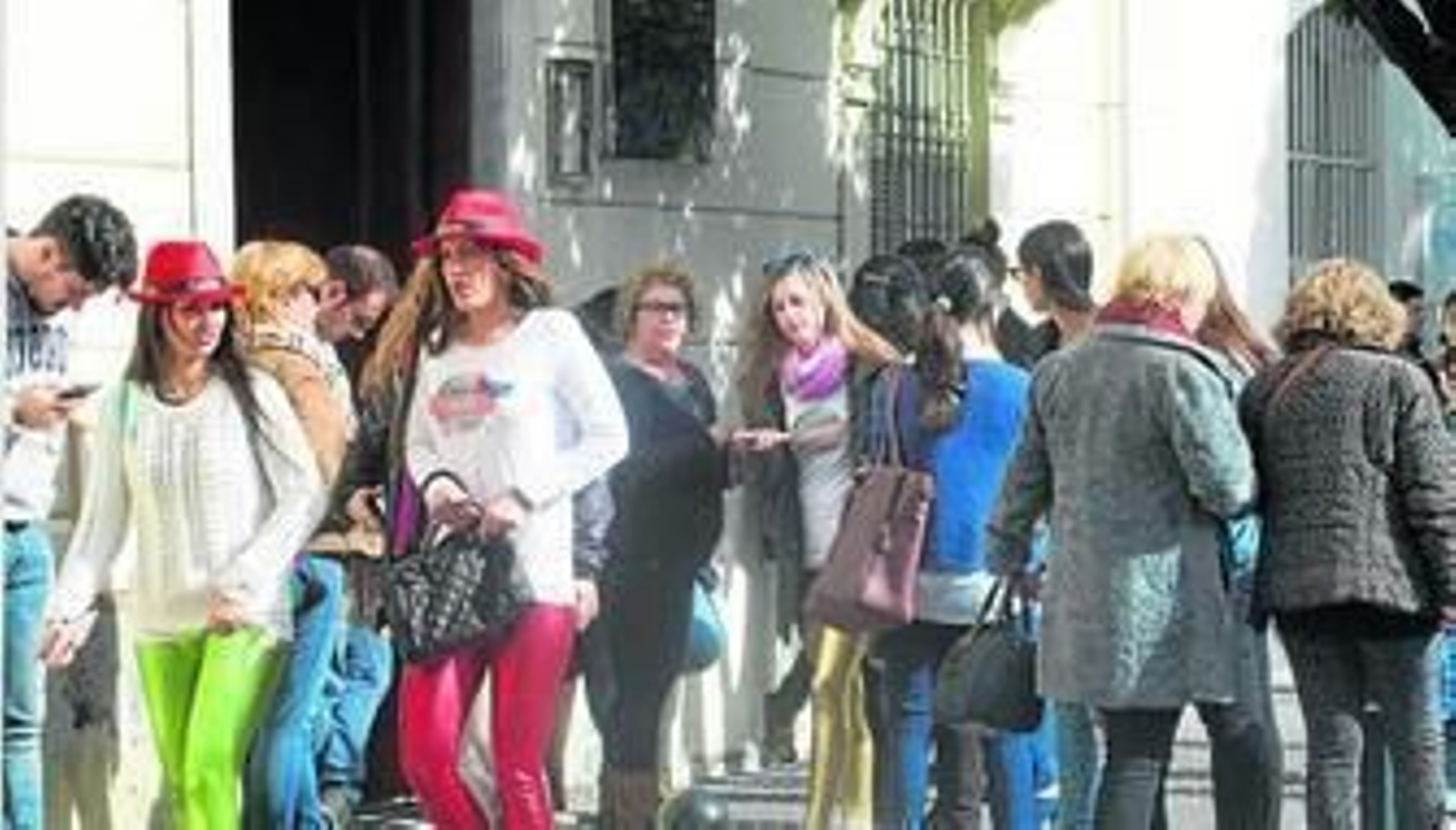 Los estudiantes esperan para examinarse en la sede de la Uned en San Antonio mientras otros viandantes se engalanan con toques carnavalescos.