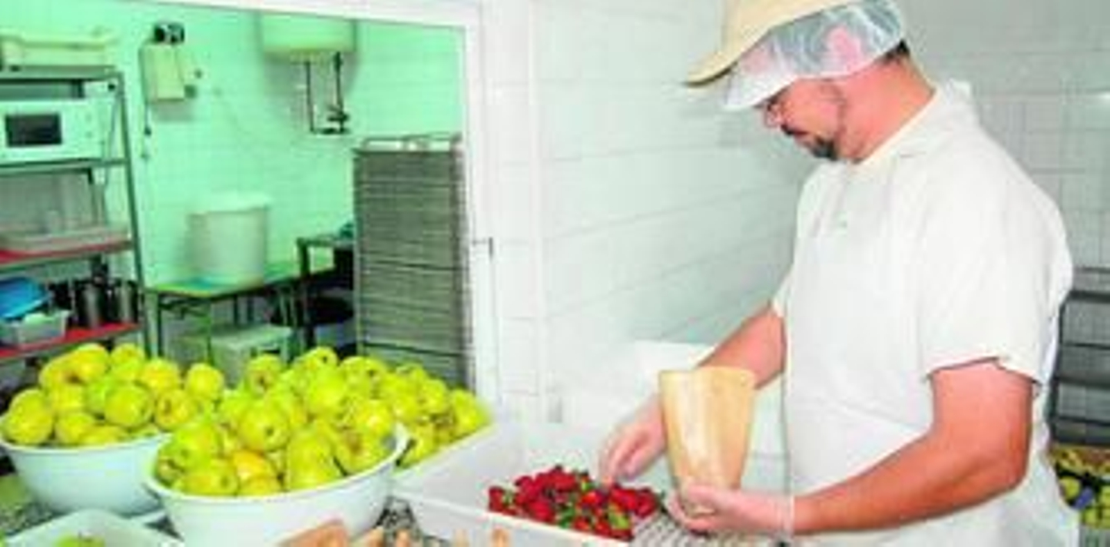 Un trabajador prepara bolsas de fruta en un comedor escolar.