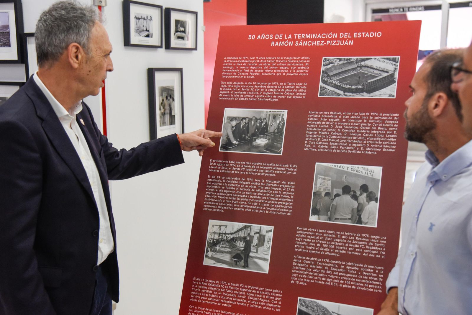 Joaquín Caparrós enseña uno de los paneles de la exposición al nieto del arquitecto José Galnares.