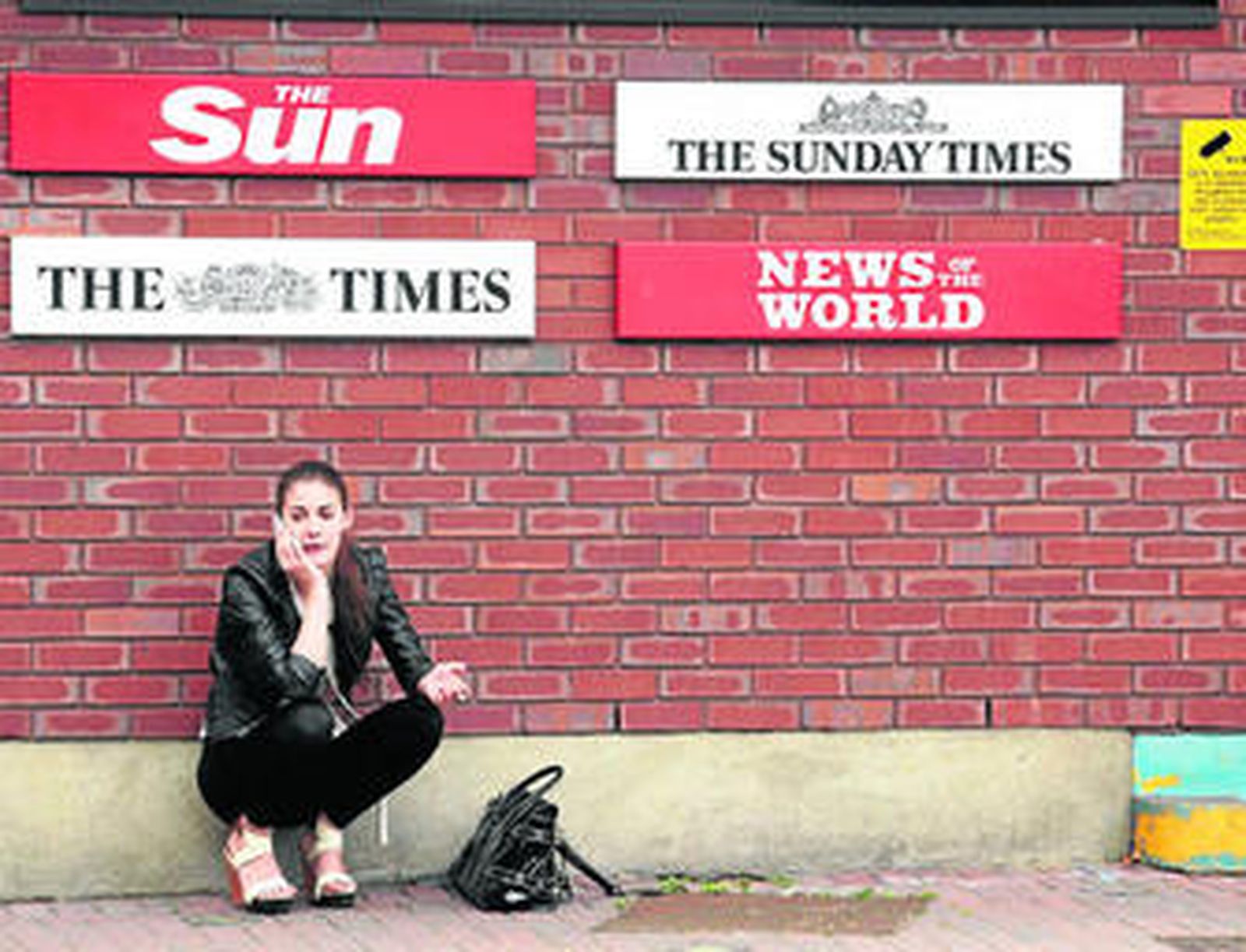 Una mujer habla ayer por el móvil en la entrada del edificio de News International, en Londres.