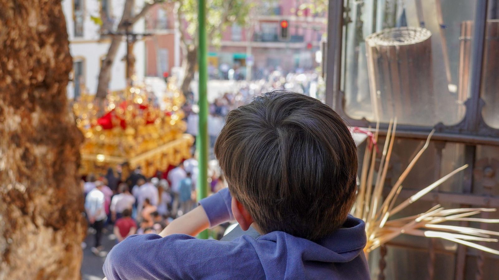 Un niño contempla el paso del Cristo de la Sed desde un balcón.