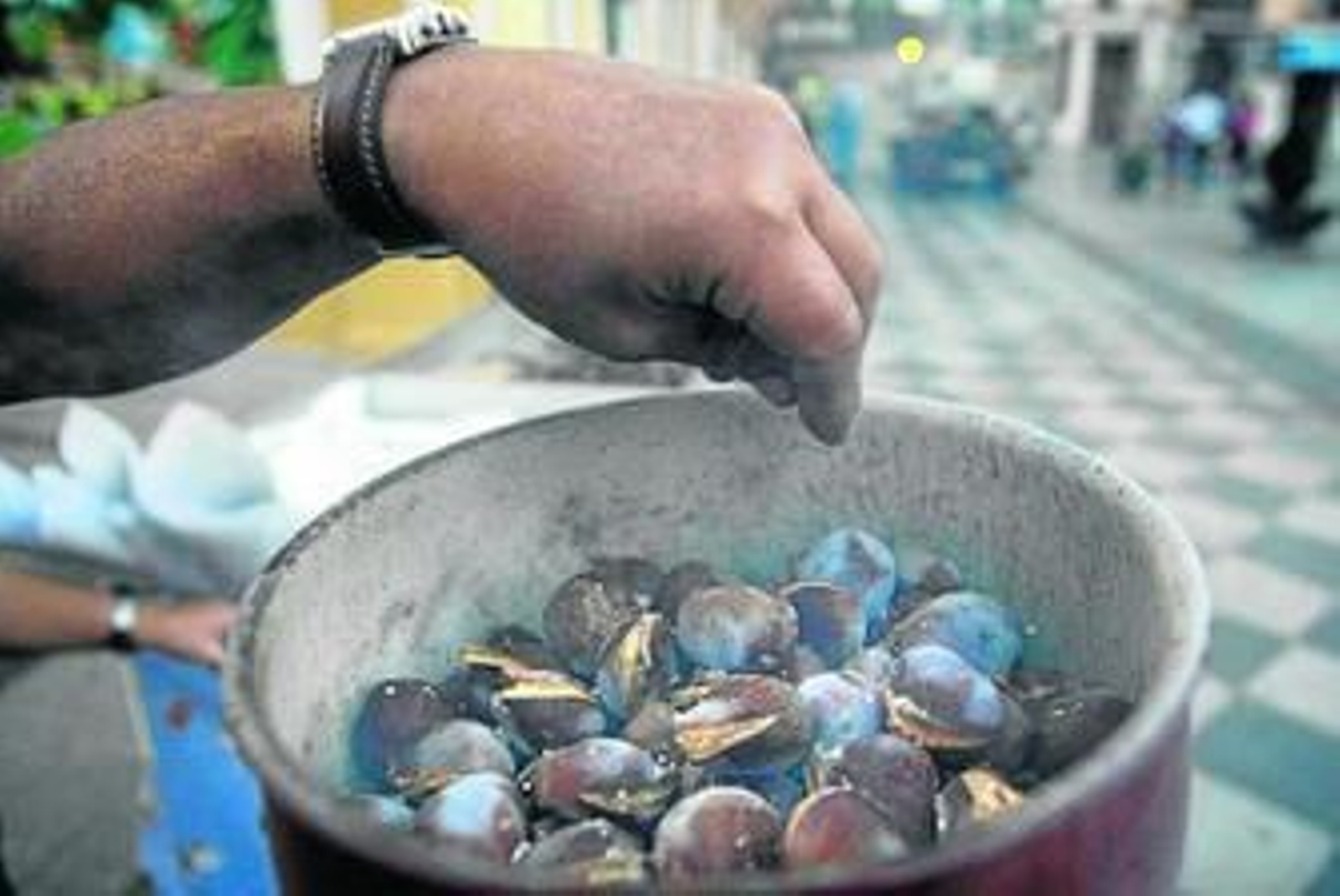 Un vendedor echa sal a las castañas en su puesto de Algeciras.