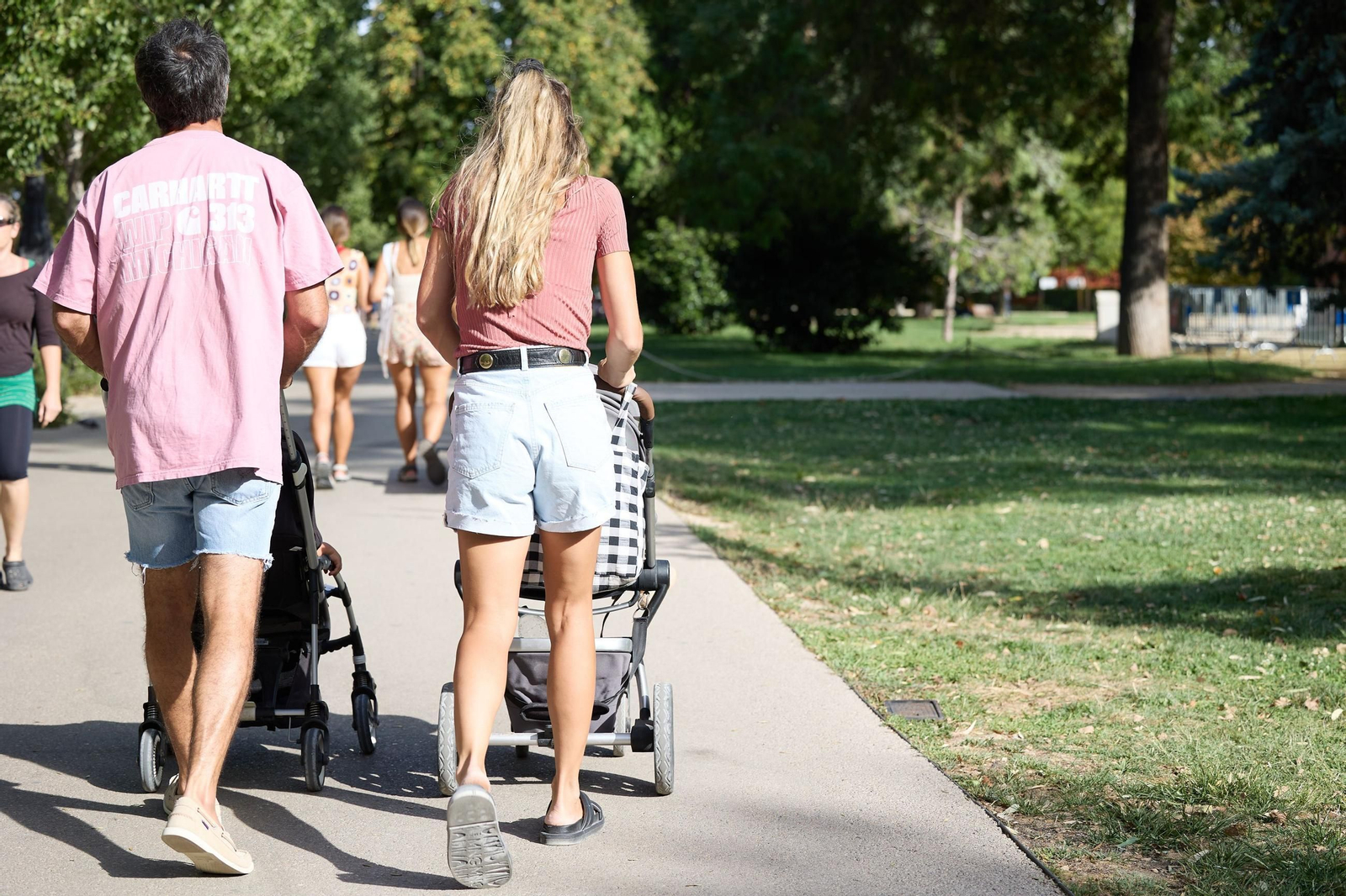 Una pareja pasea a sus hijos por el parque.