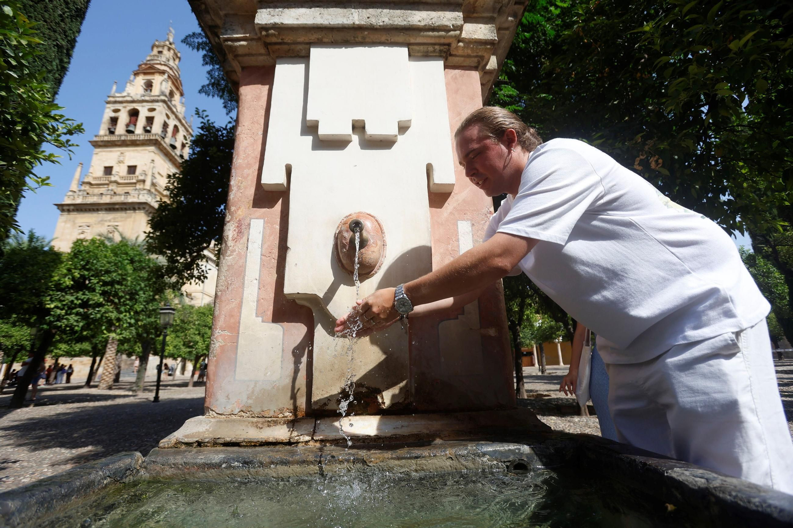 Un joven se refresca en una de las fuentes del Patio de los Naranjos de la Mezquita-Catedral.