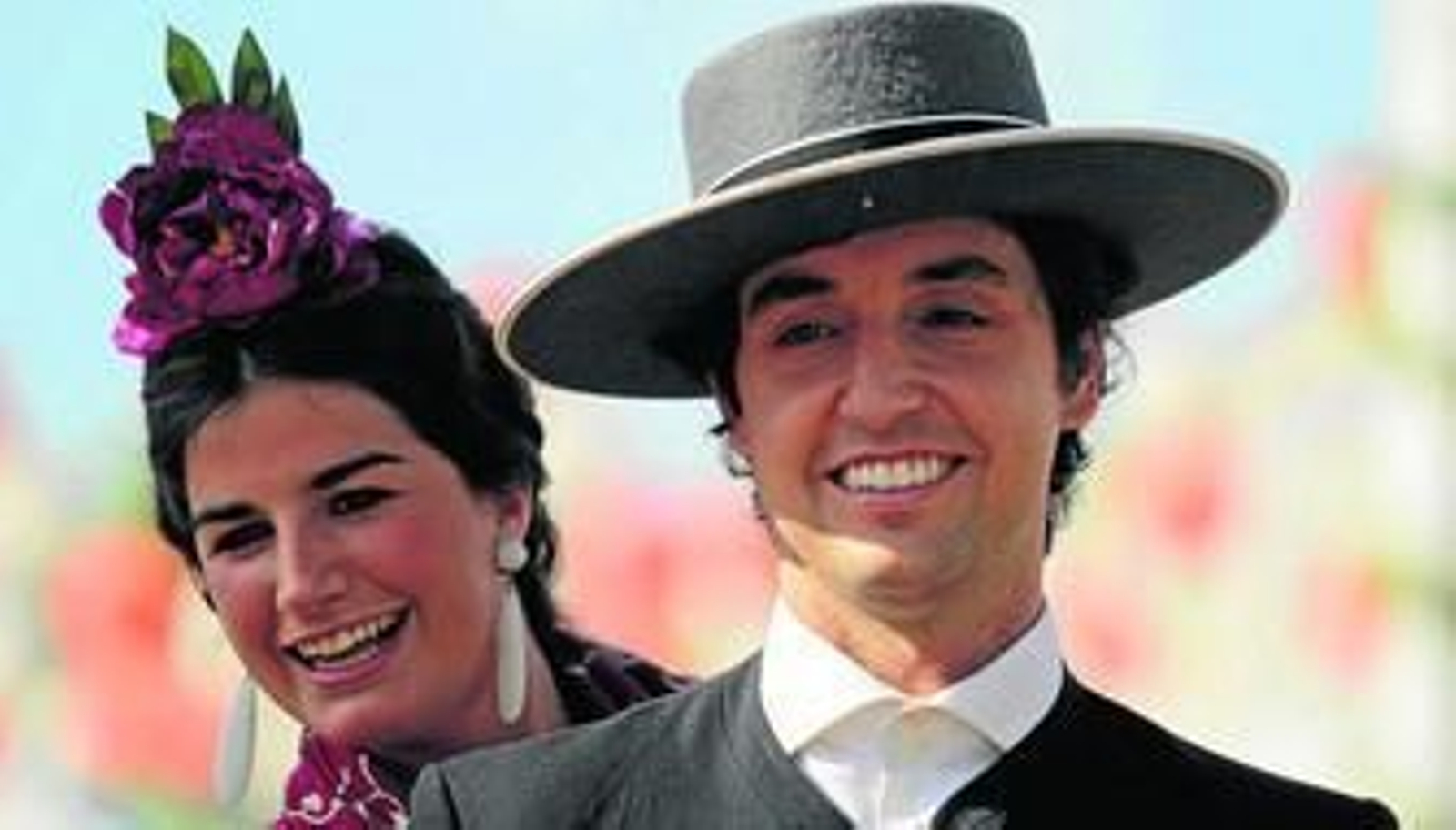 Un jinete y una flamenca a la grupa sonríen durante su paseo ayer por las calles del real.