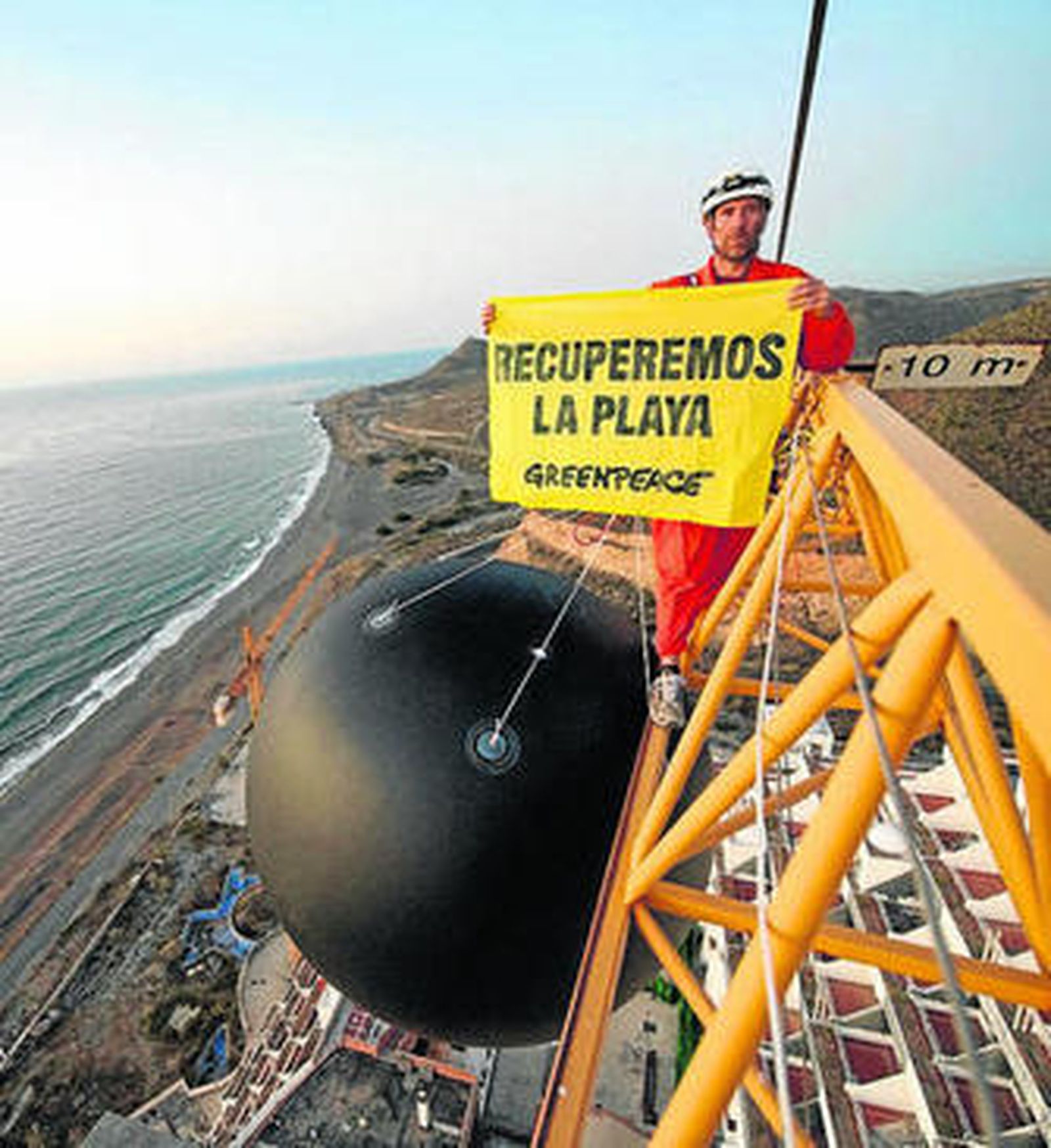 Un activista de Greenpeace, sobre una de las grúas del hotel almeriense.