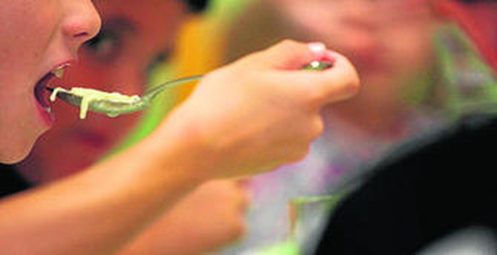 Un niño come unos fideos en un comedor escolar.