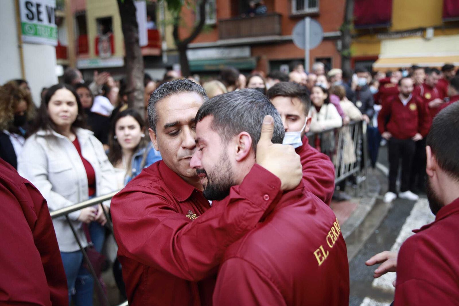 Dos costaleros del Cerro se abrazan tras conocerse la suspensión de la estación de penitencia.