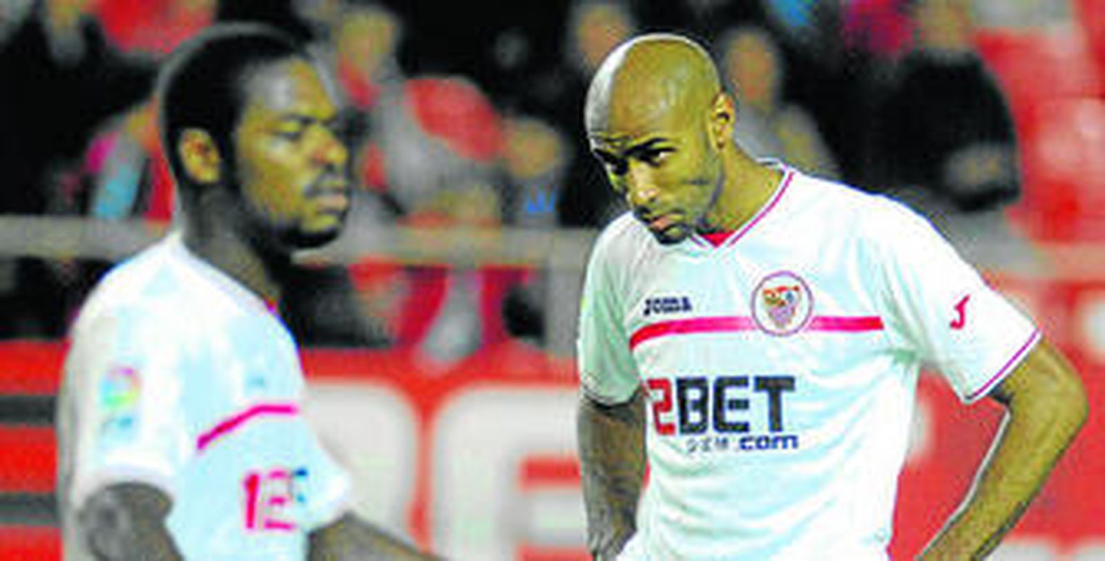 Kanoute se desespera y mira con mala cara a un punto indefinido; Romaric aparece difuminado.