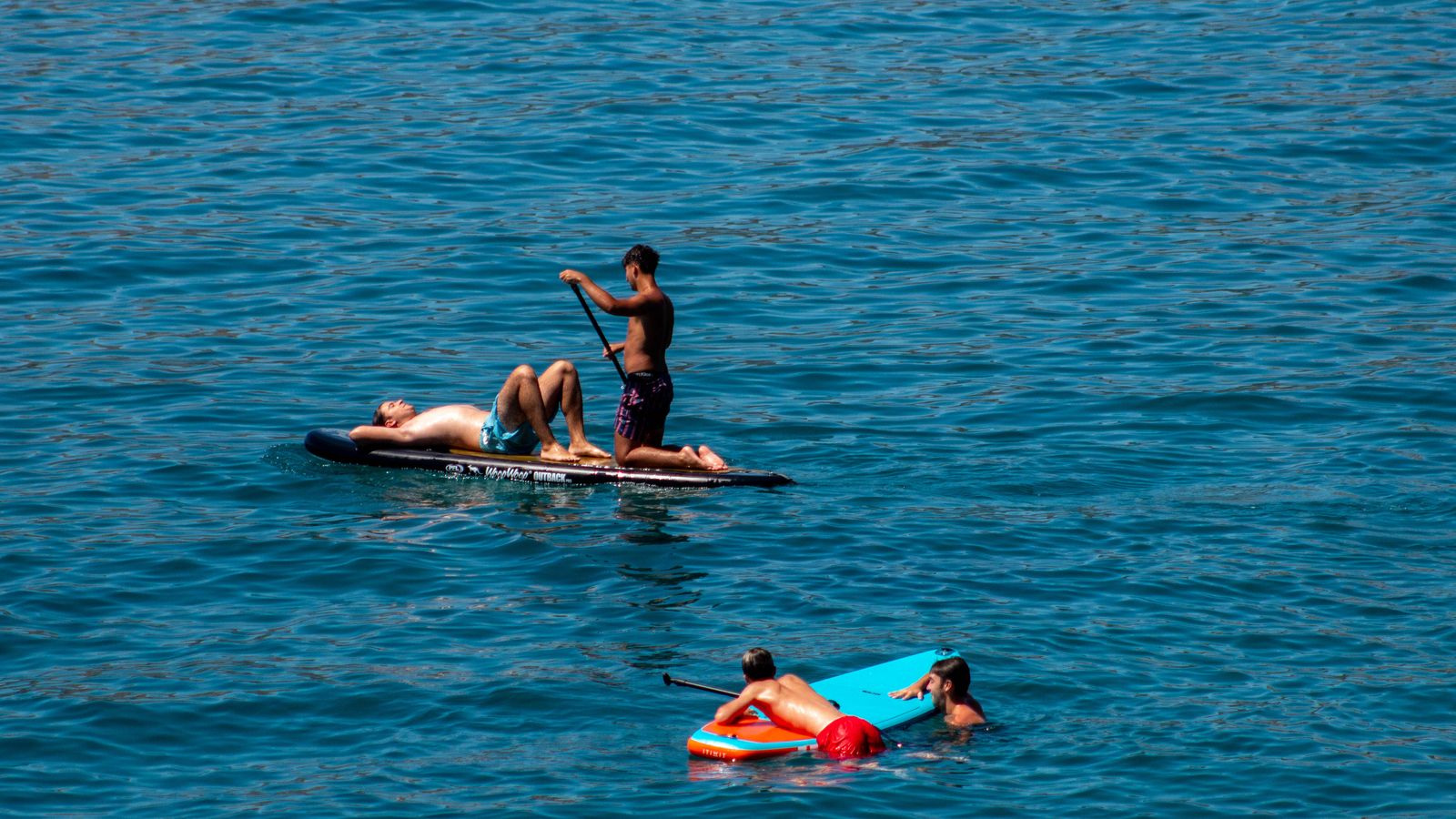 Varios jóvenes disfrutando de la playa con sus tablas de paddle surf