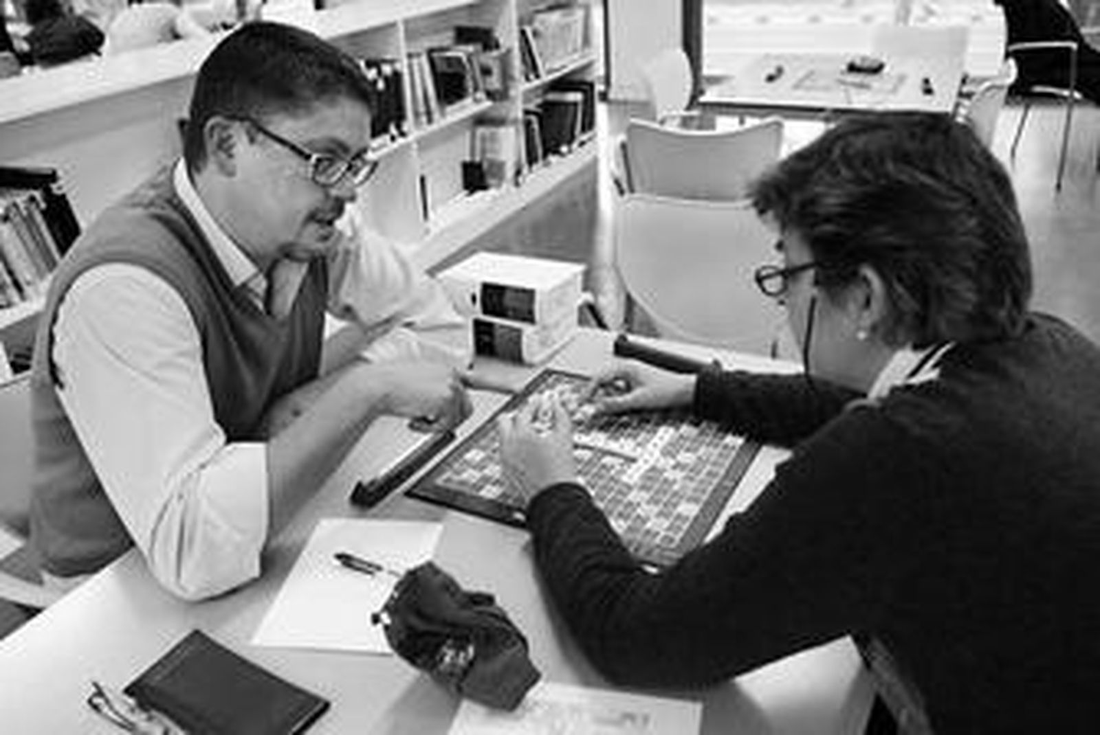 Dos jugadores conversan en plena partida de Scrabble, y con el diccionario sobre la mesa.