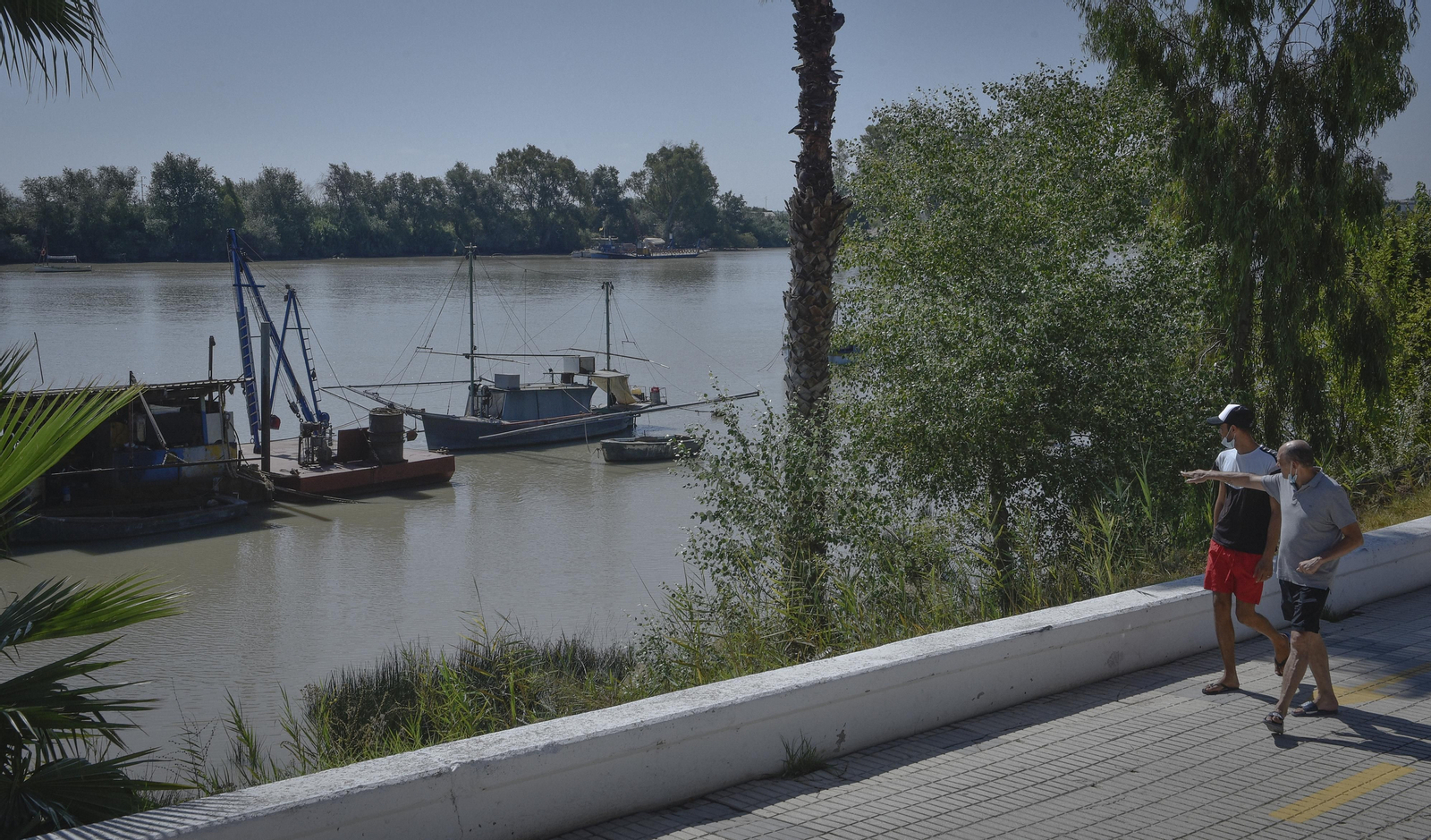 Dos personas pasean junto al río Guadalquivir en Coria del Río.
