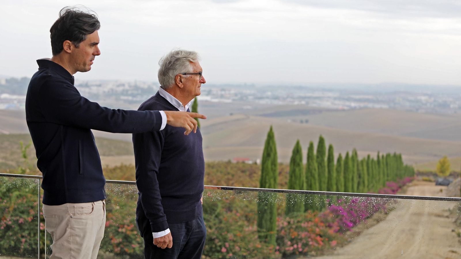 El joven enólogo de la familia Pérez conversa con su padre en la bodega con las vistas de Jerez al fondo.