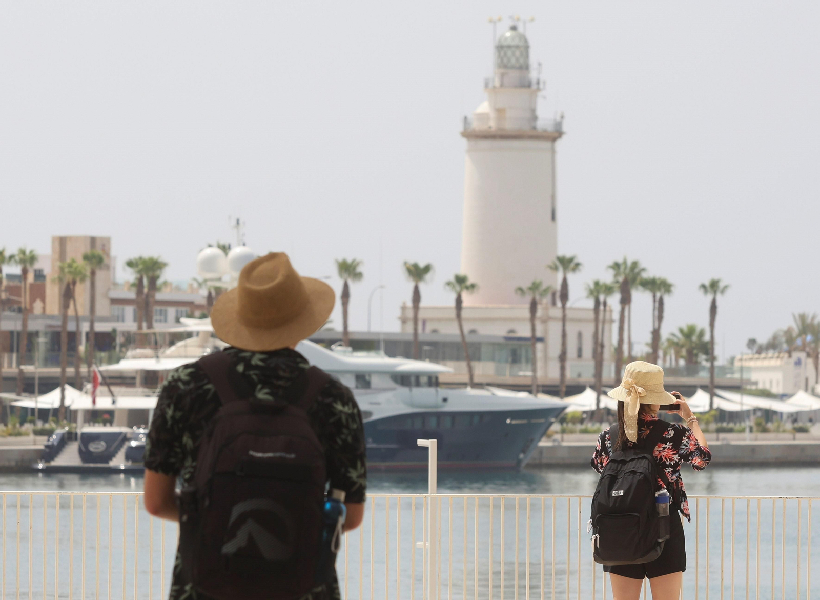 Dos personas se protegen del calor con sombreros.
